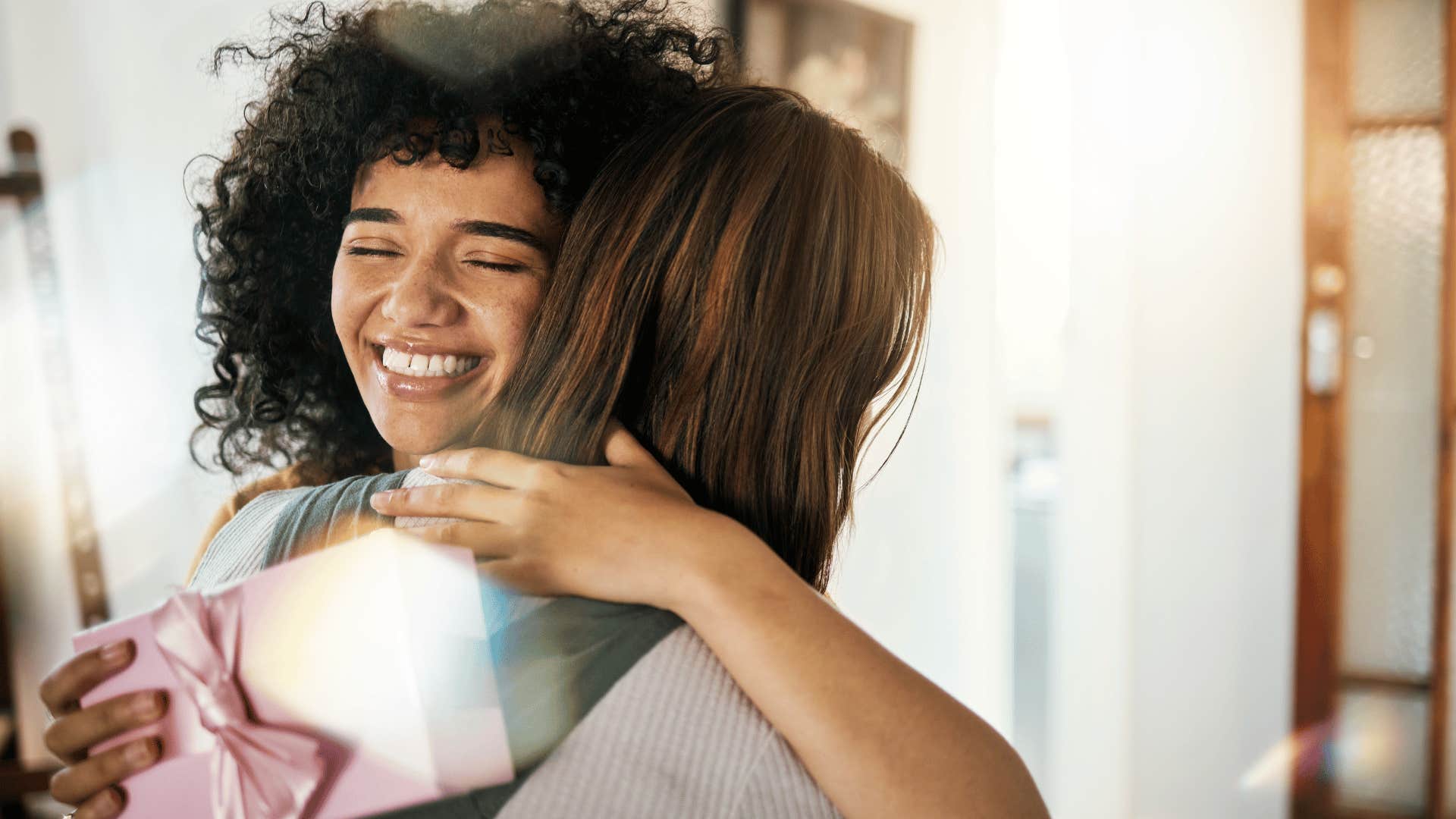 woman hugging friend and giving her a gift
