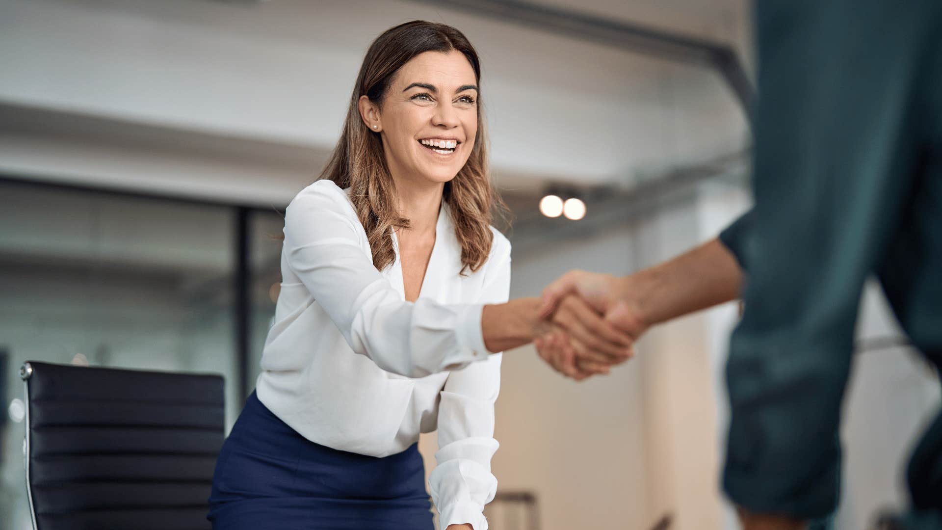 woman saying thank you shaking person's hand