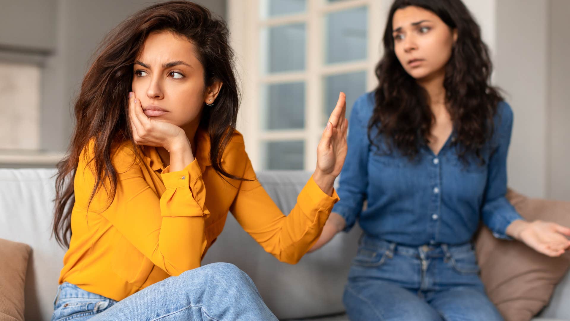 Woman saying "calm down" while turned away from her friend.