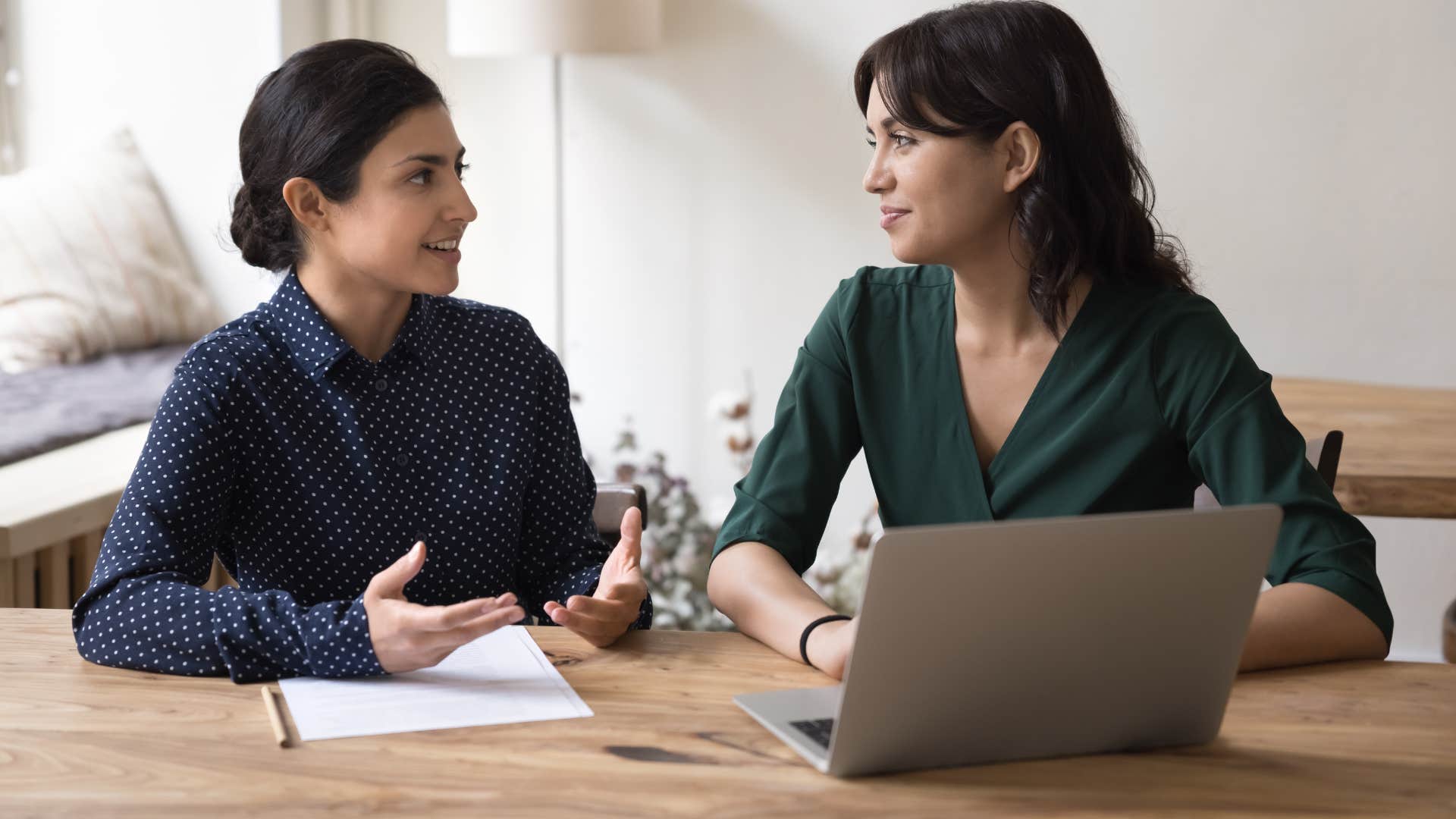woman in navy blue shirt asking woman what's something you're learning about right now while they sit at a desk