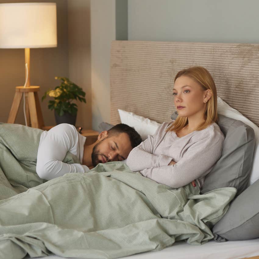 upset woman in bed next to wrong person she's in love with