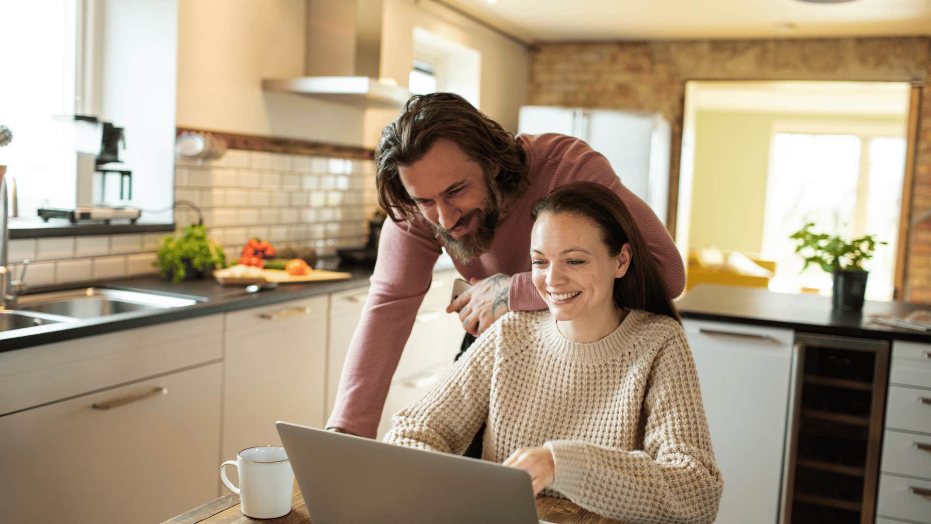 man who is memorable to woman at laptop over woman's shoulder