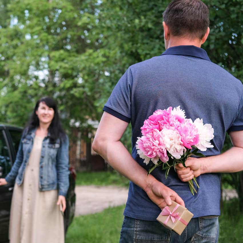 man holding flowers behind back who is unforgettbale