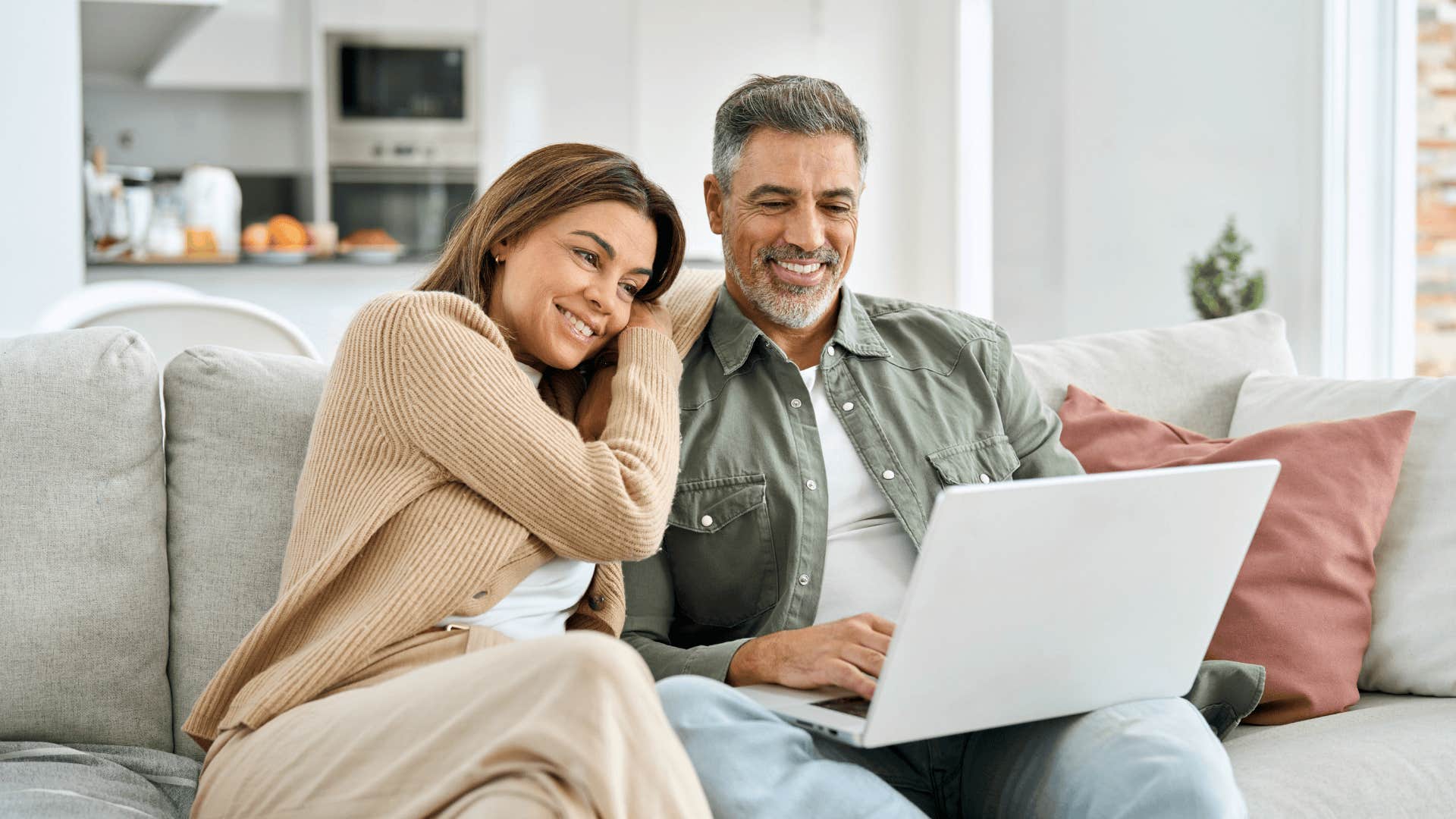 smiling impressive woman cuddled up with man on laptop