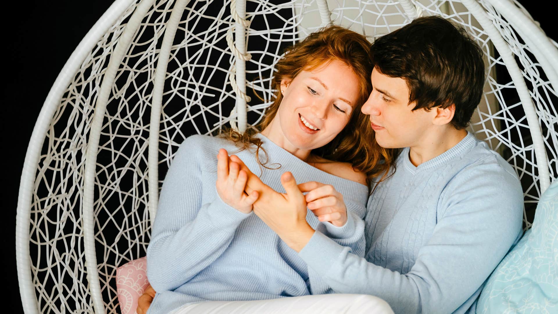 couple cuddling in a swing chair content doing nothing together 