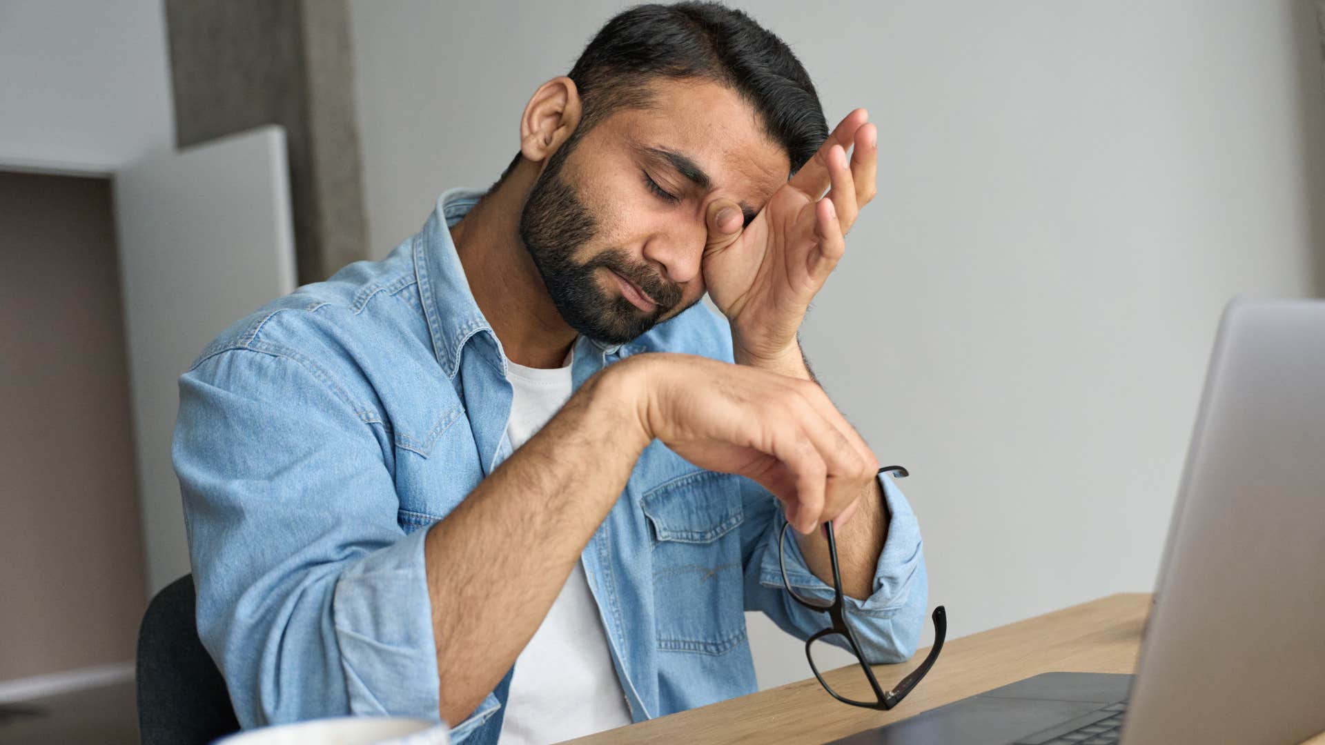 stressed man rubbing his eyes from being too tired