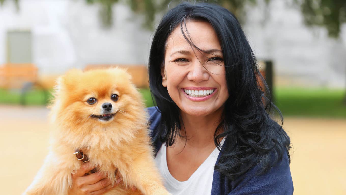 older woman smiling holding her pet dog