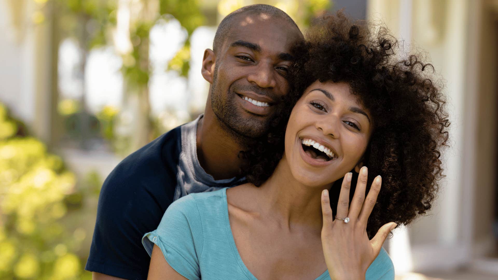 couple rushing relationship as woman holds up engagement ring and smiles while man hugs her from behind