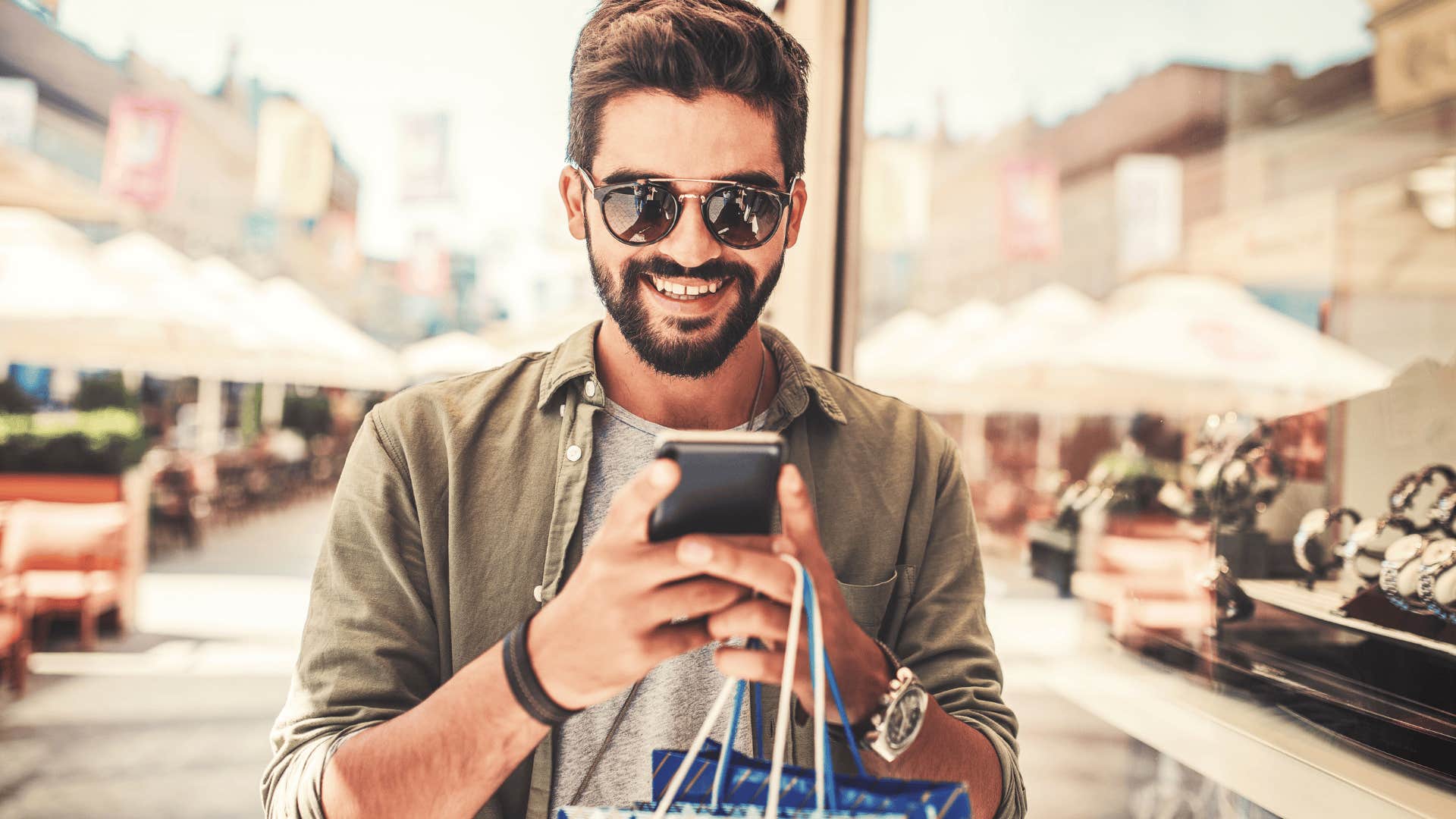 young man texting after shopping spree