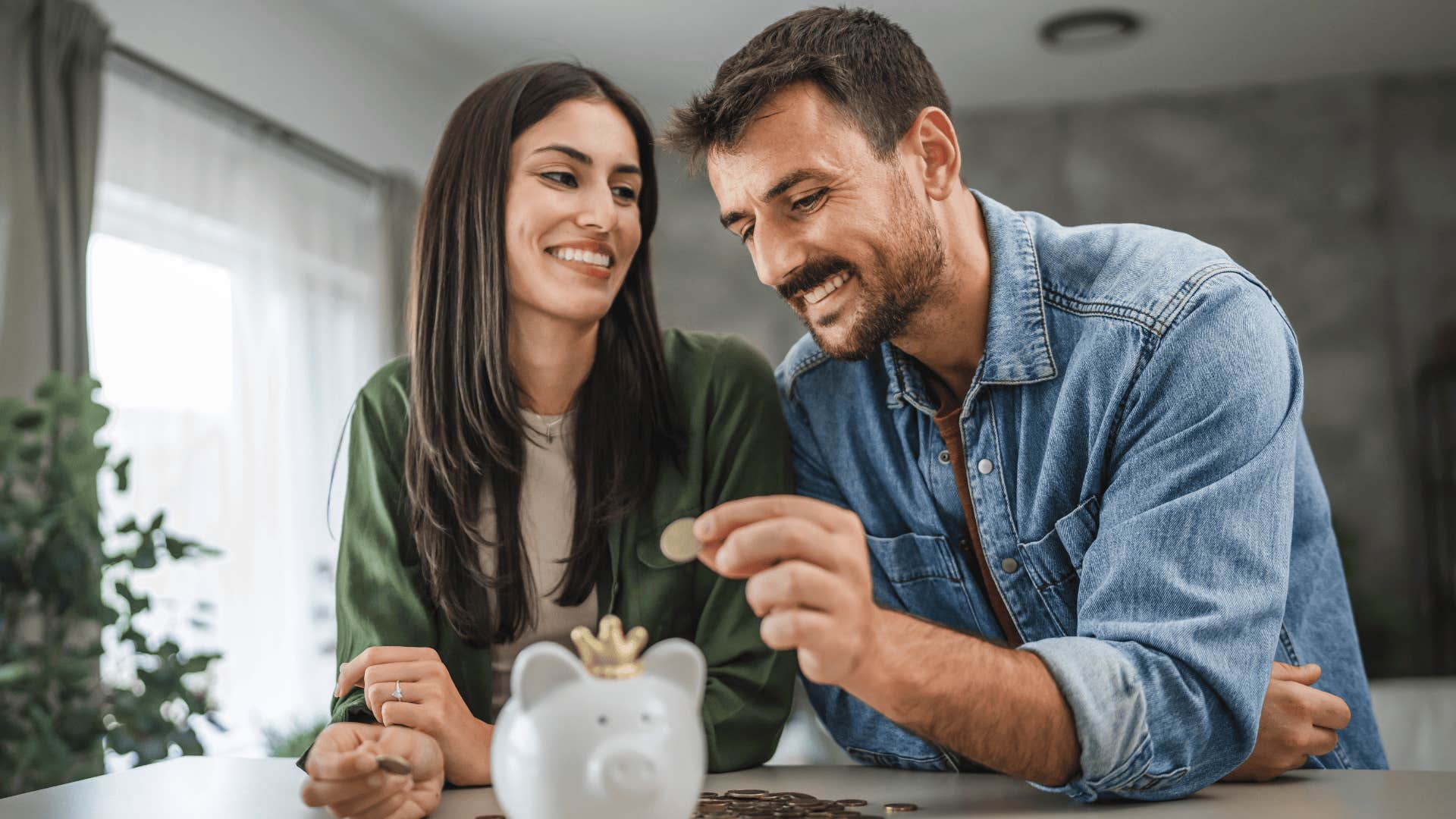 smiling couple putting money into a piggy bank