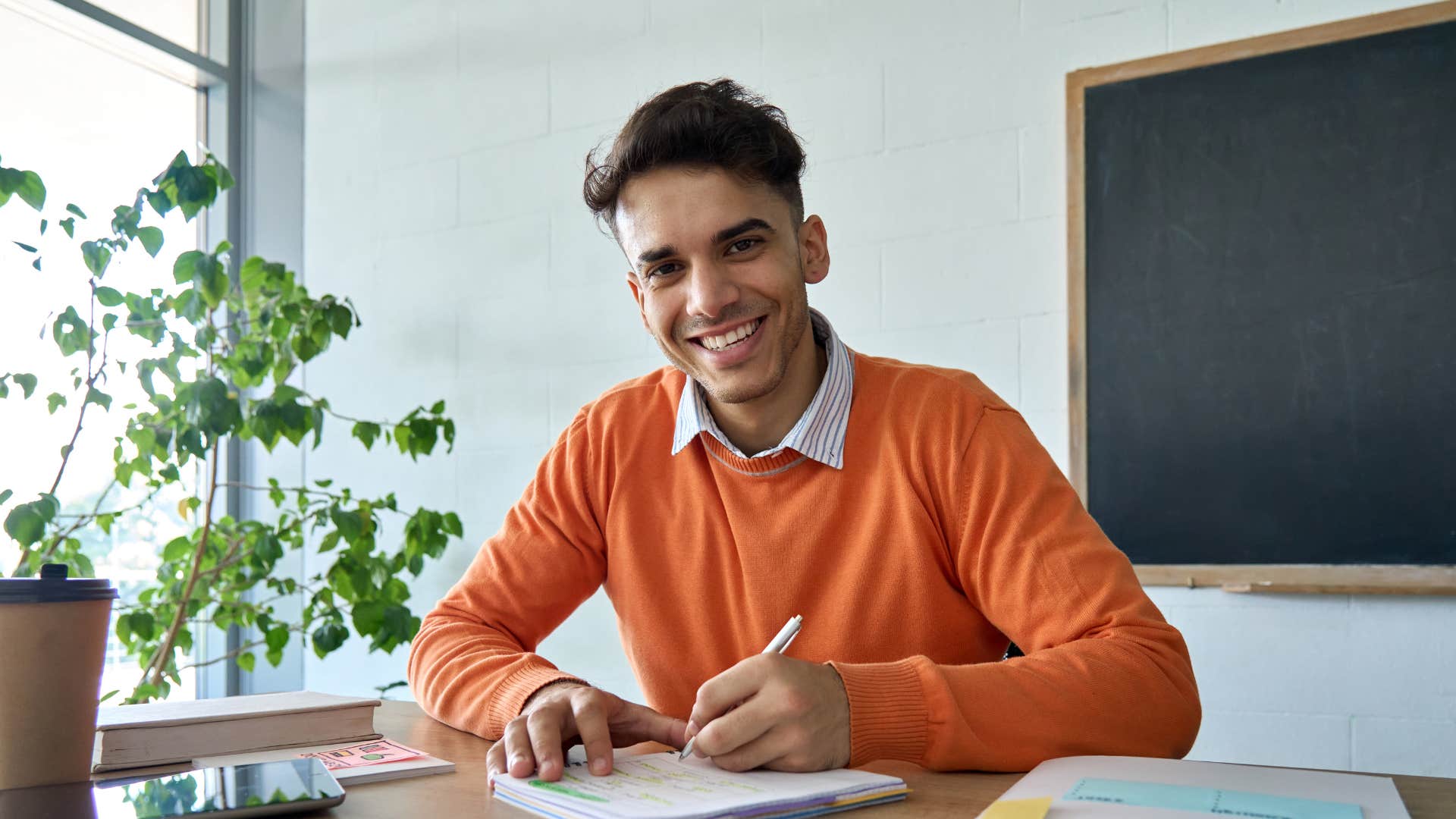 gen z man writing a paper smiling at school