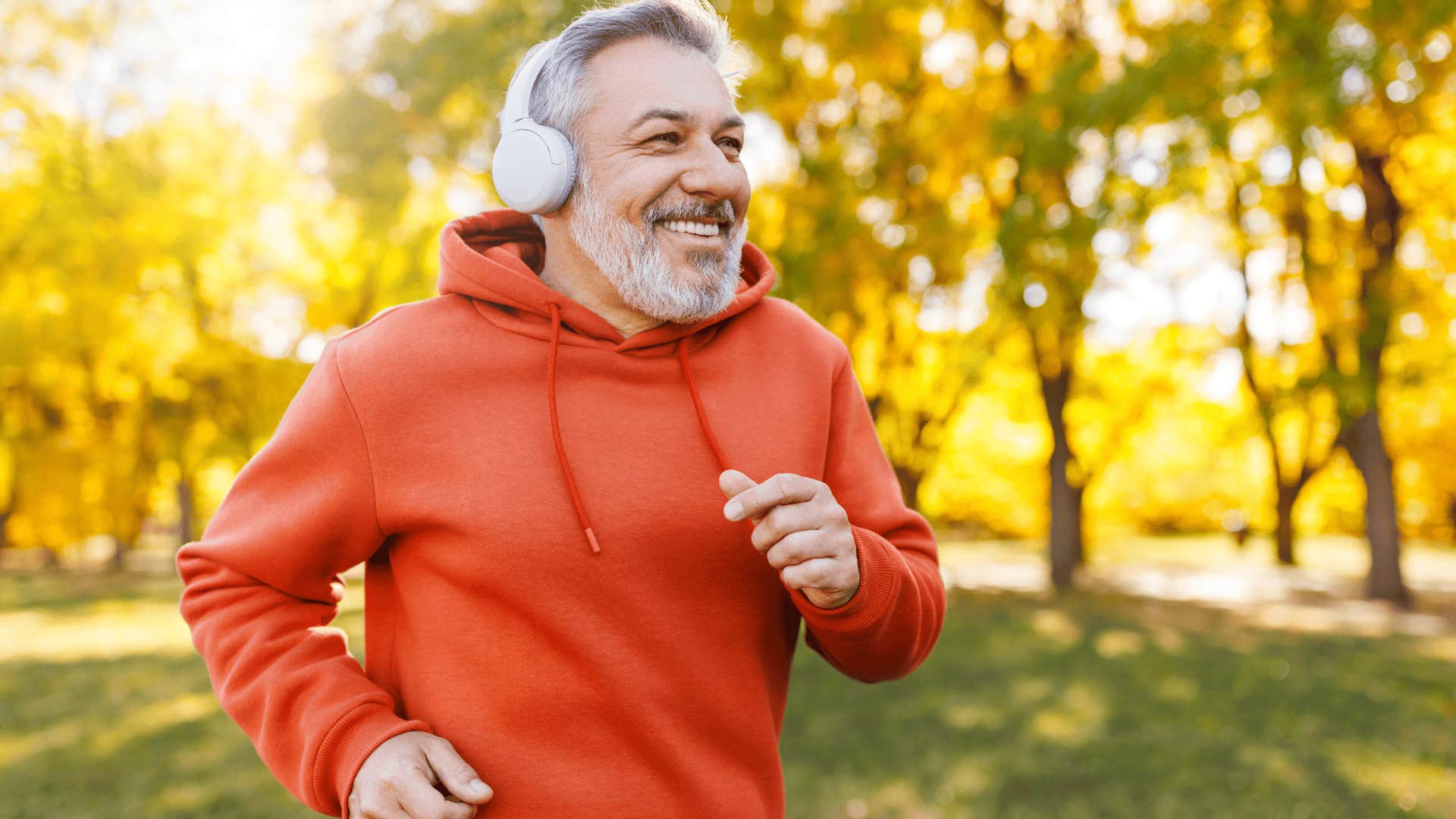 older man smiling and running outside