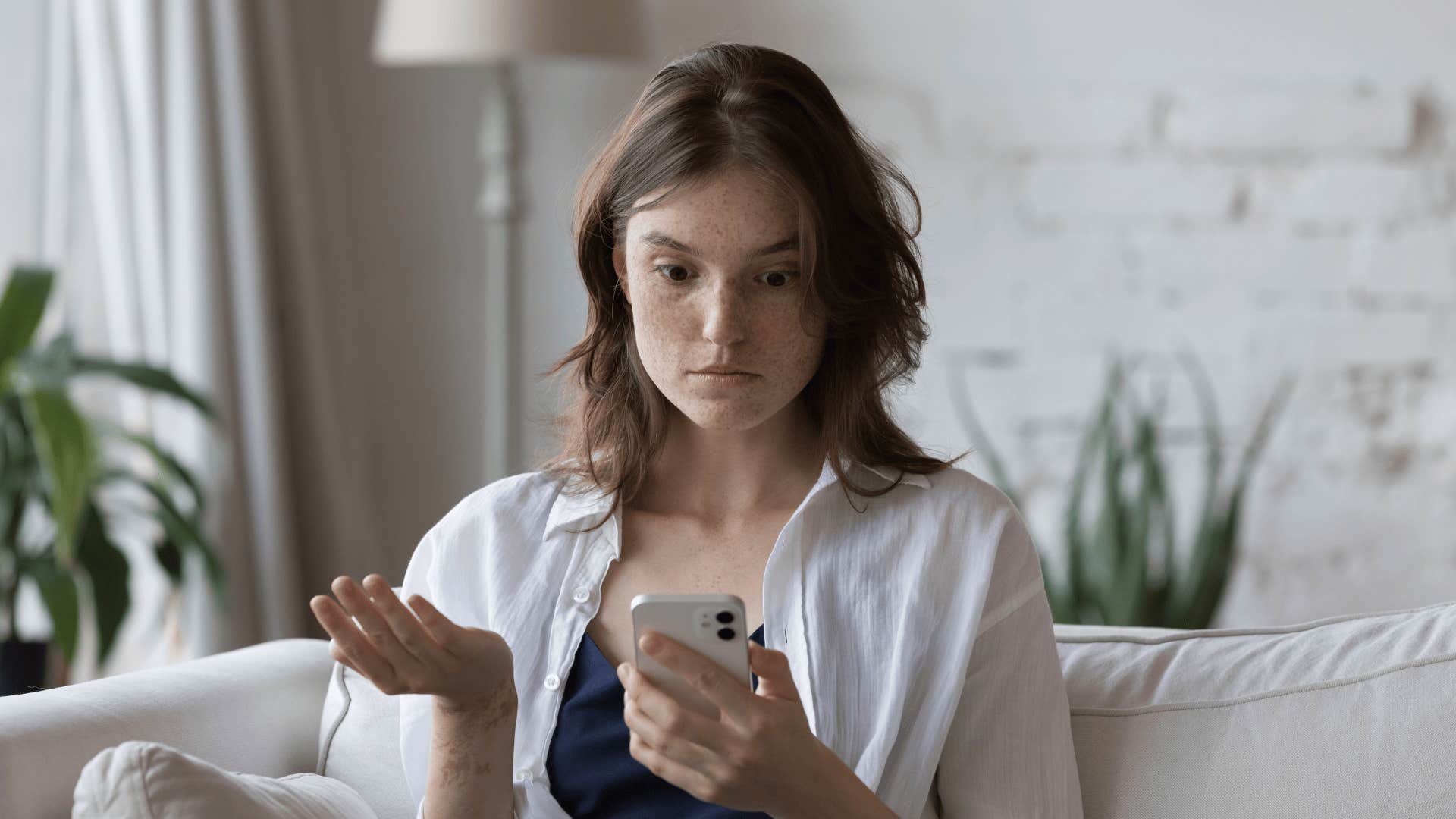 upset woman who is being breadcrumbed looking at phone