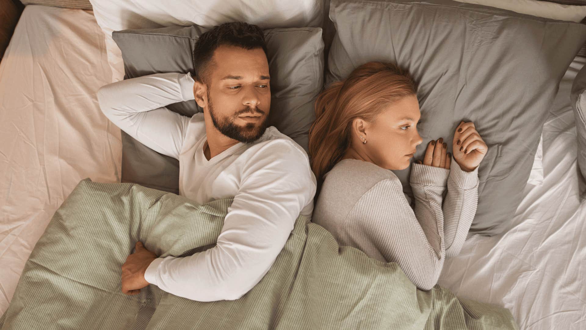 man who is being breadcrumbed looking at woman in bed