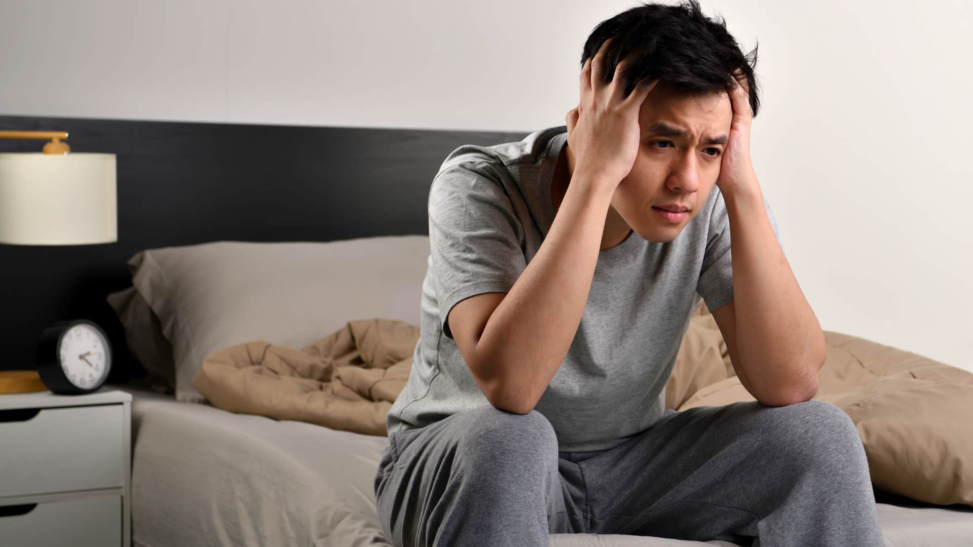 very tired man struggling to get out of bed