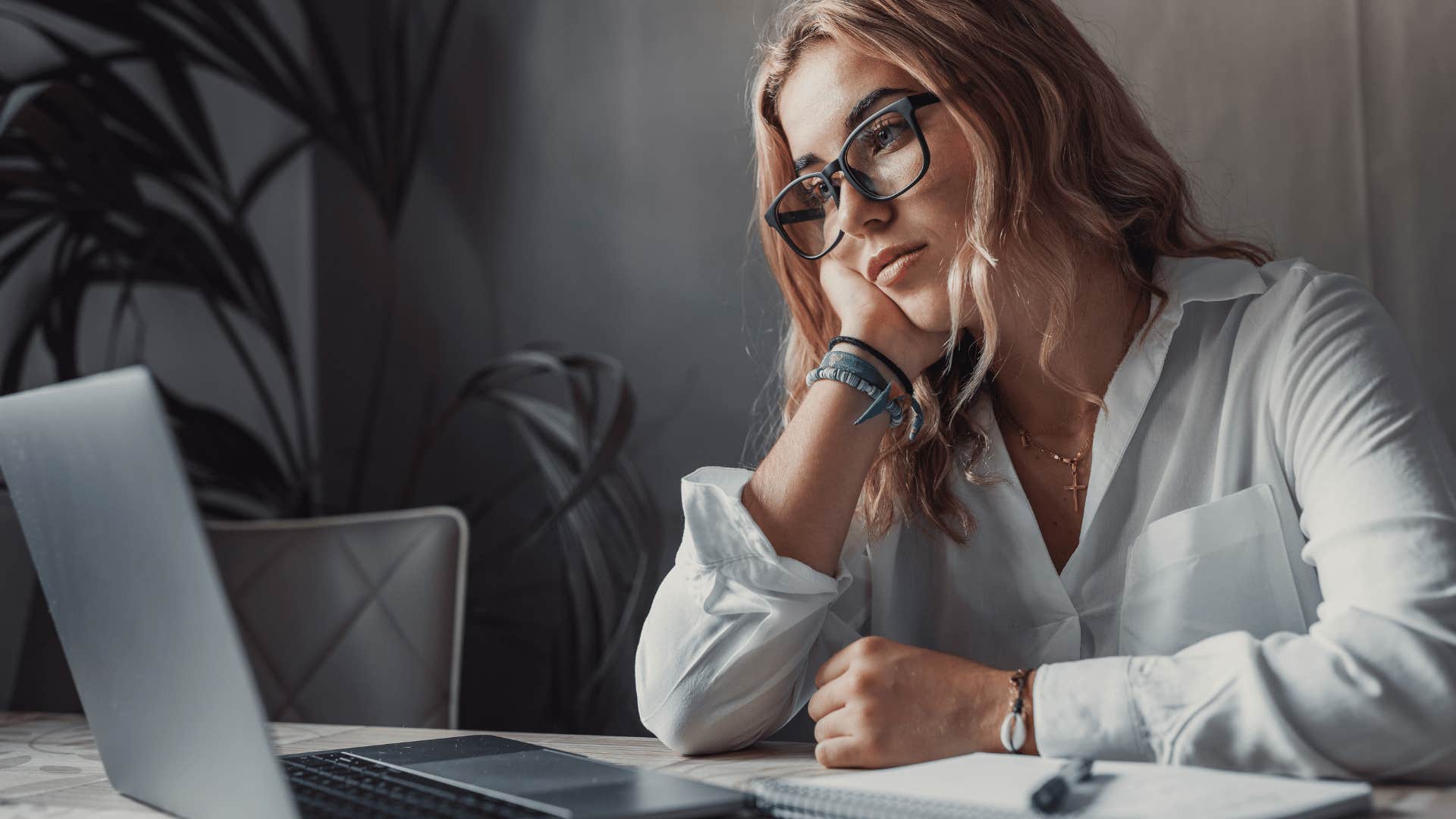 A woman shows complacency as she works on the computer.