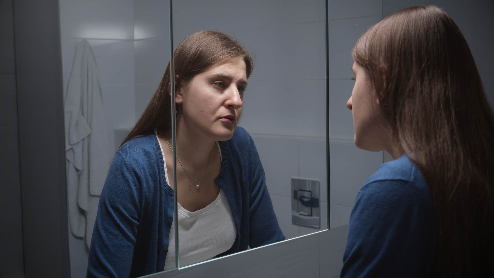 woman engaging in negative self-talk in the mirror