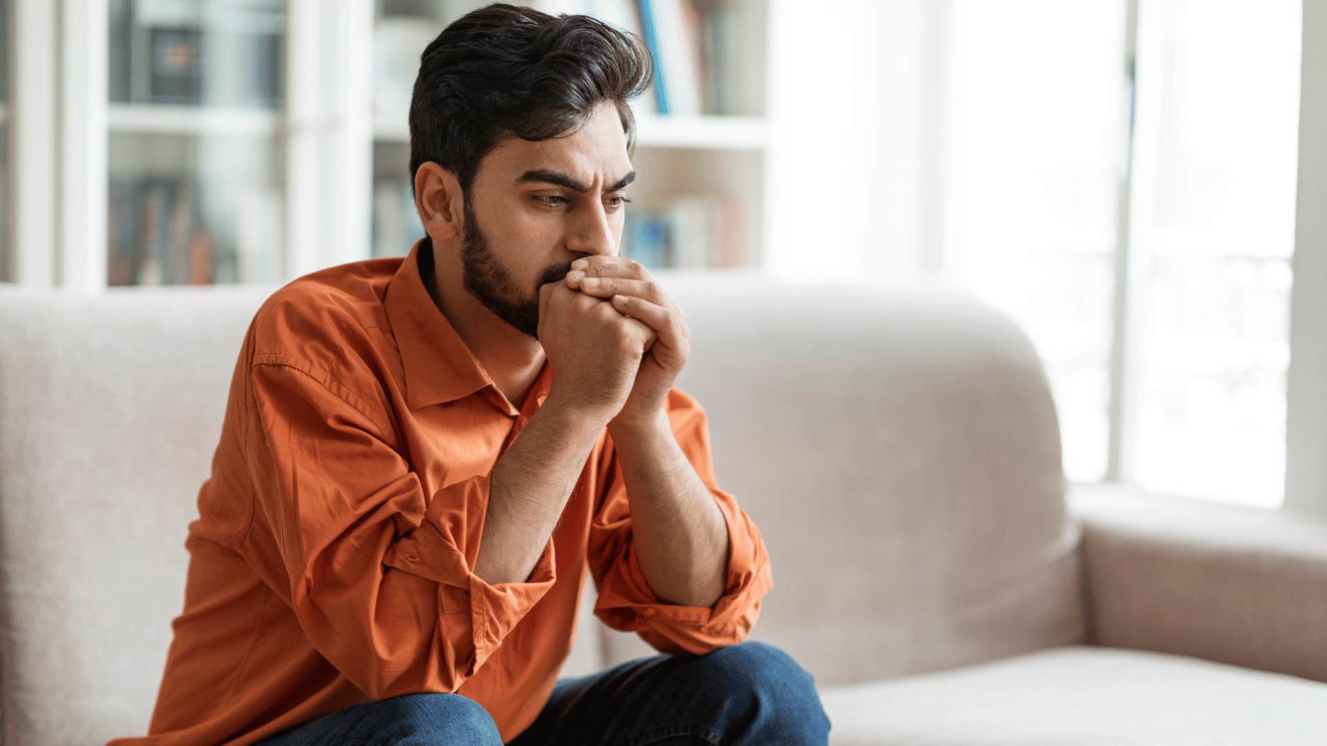 unusually quiet husband sits on the couch with his head in his hands