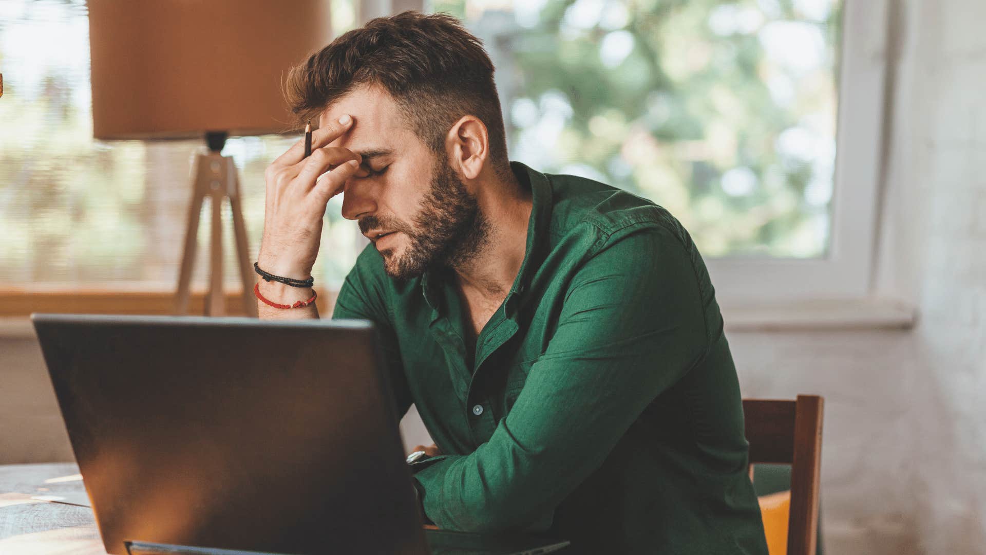 visibly tired husband rests his head in his hands
