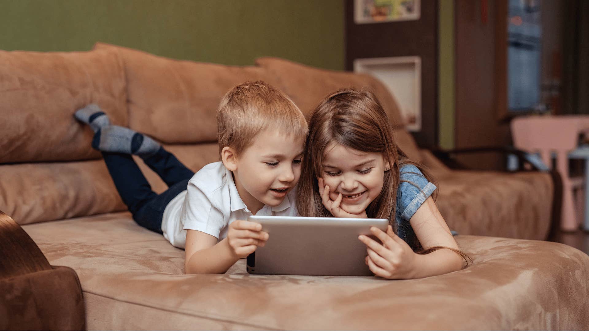 sister practices by showing little brother how to use laptop
