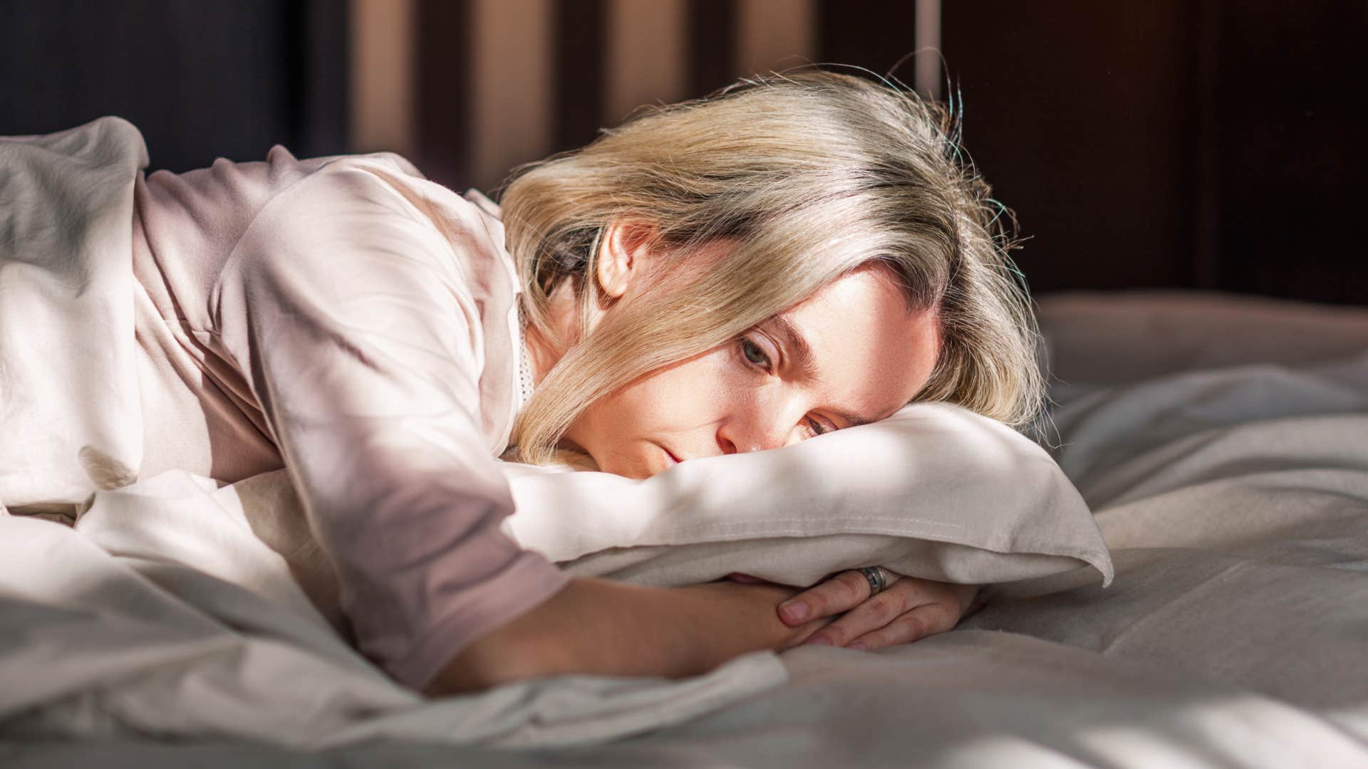 sad woman struggling to get up with her alarm laying in bed