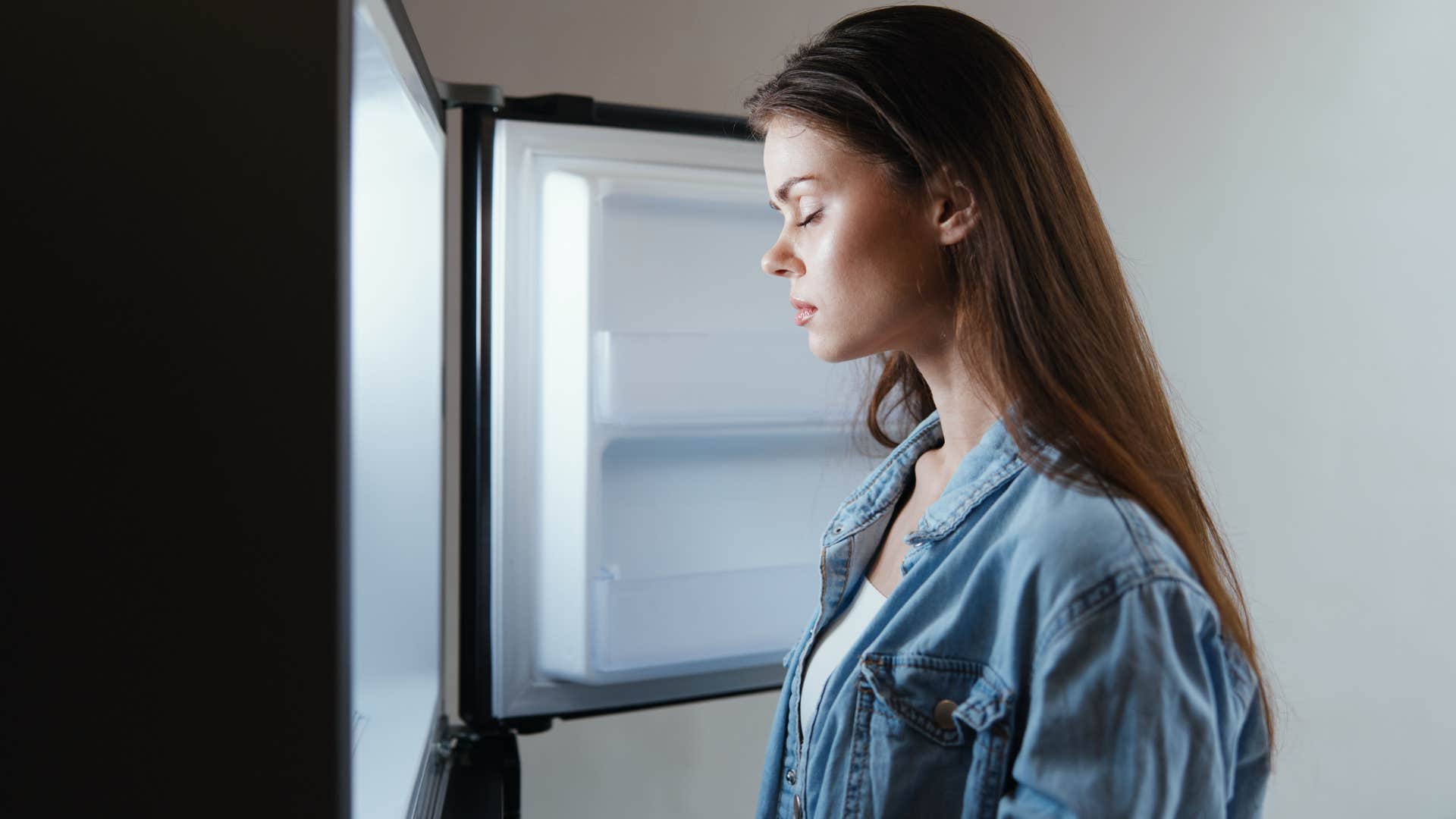 woman standing in front of freezer trying to choose what to eat