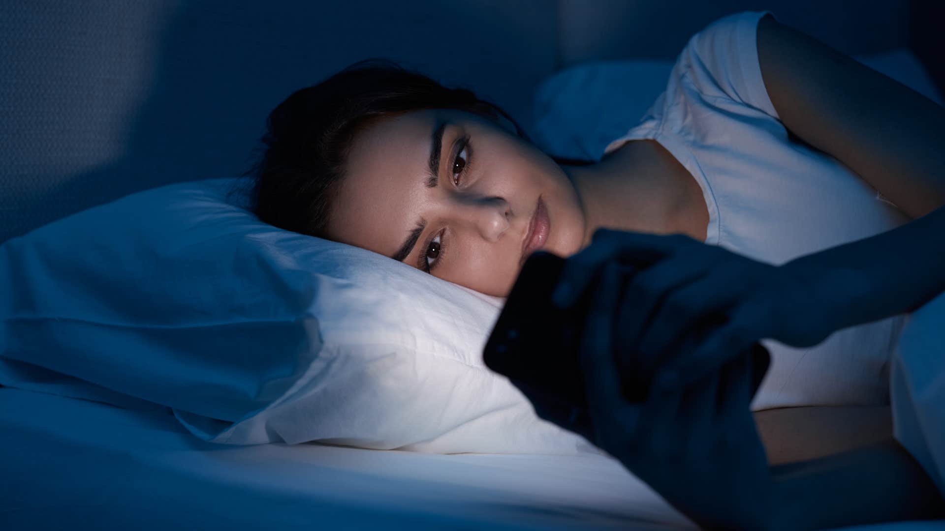 woman avoiding falling asleep by being on her phone