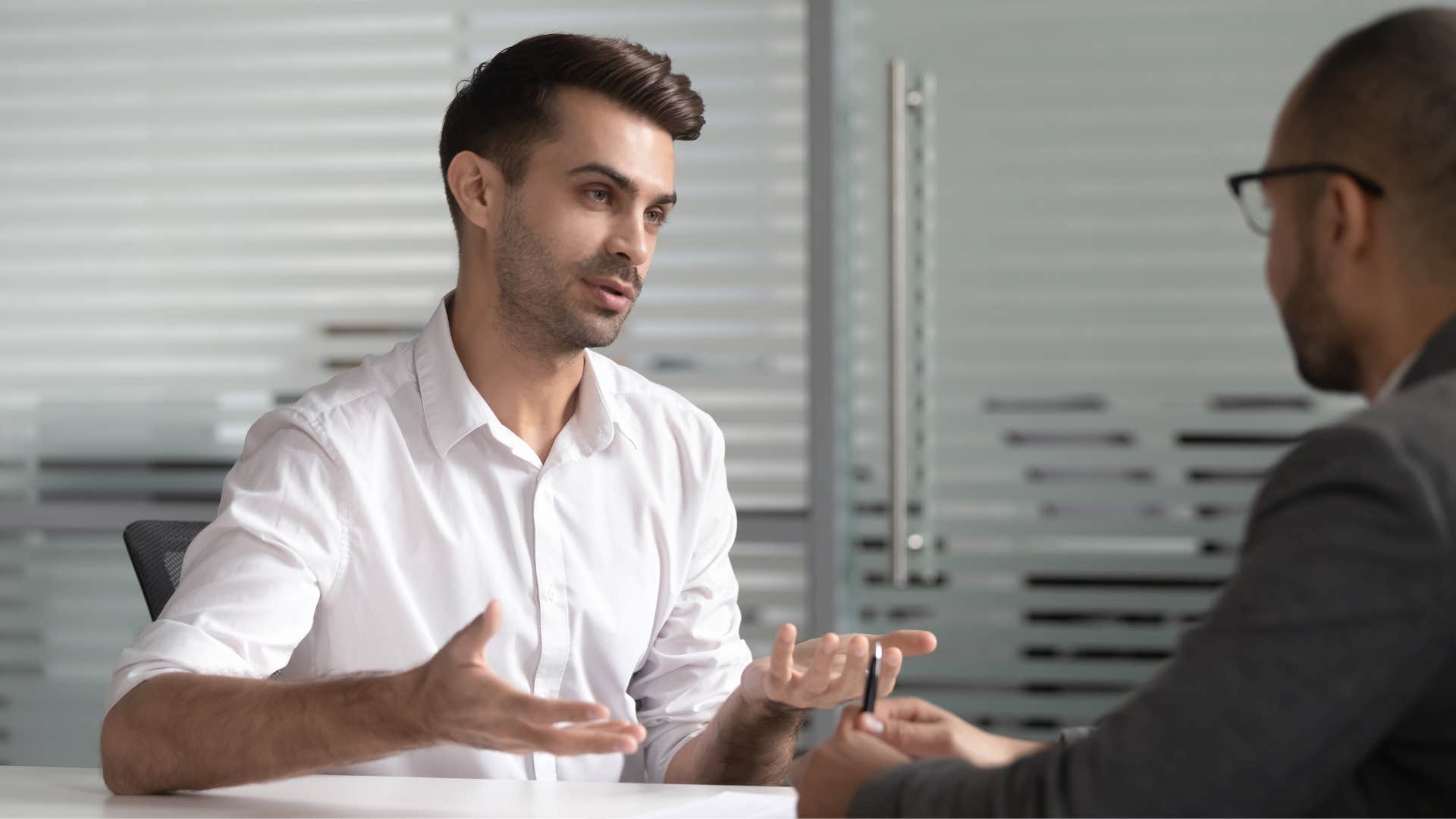 man in white shirt telling coworker he doesn't seem like the type 