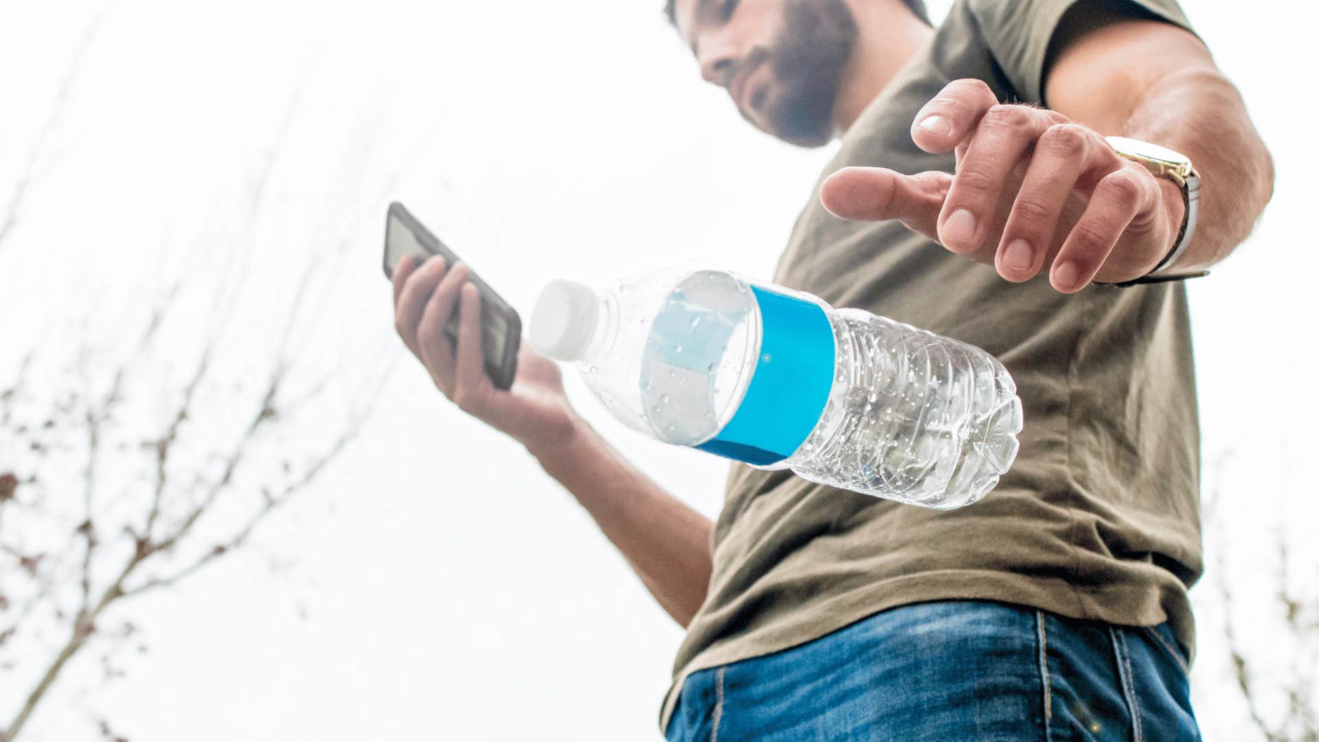 mandropping water bottle onto the ground littering