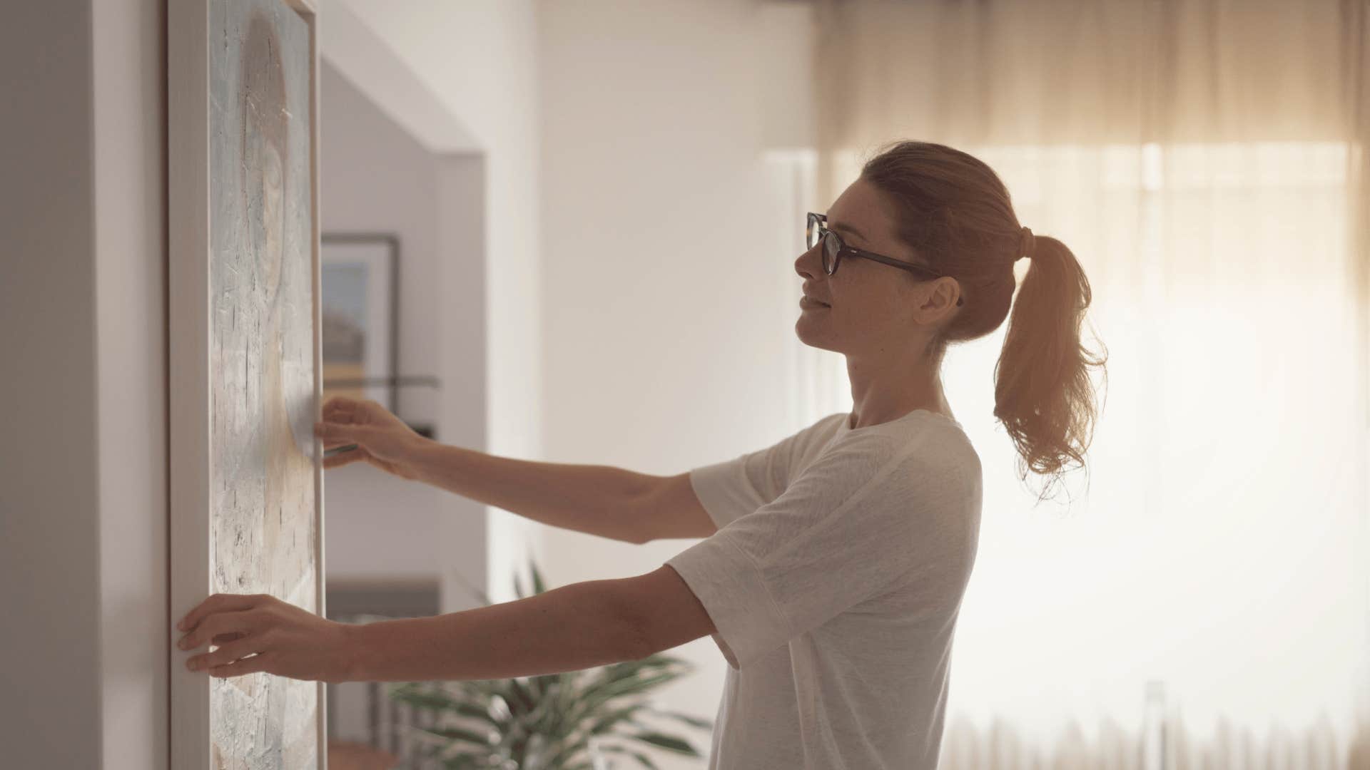 millennial woman hanging painting