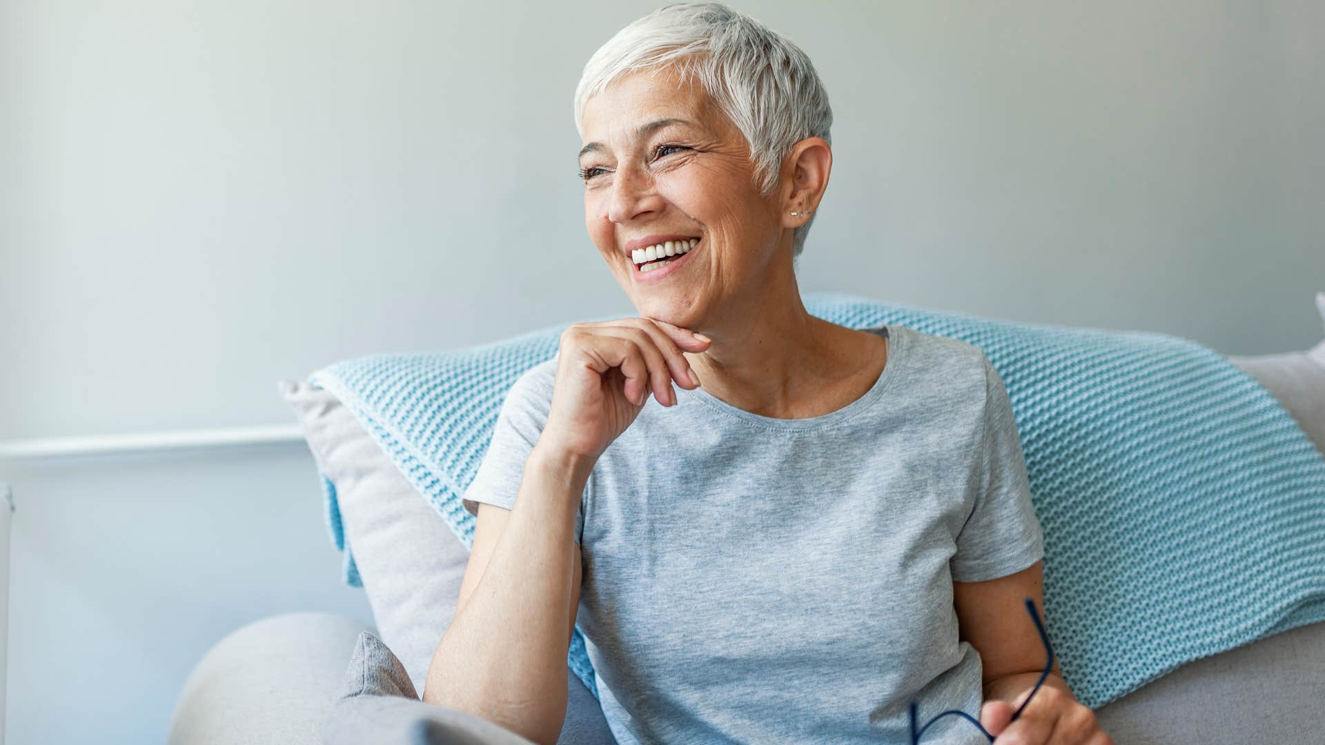 Woman with delayed gratification skills smiling on the couch.