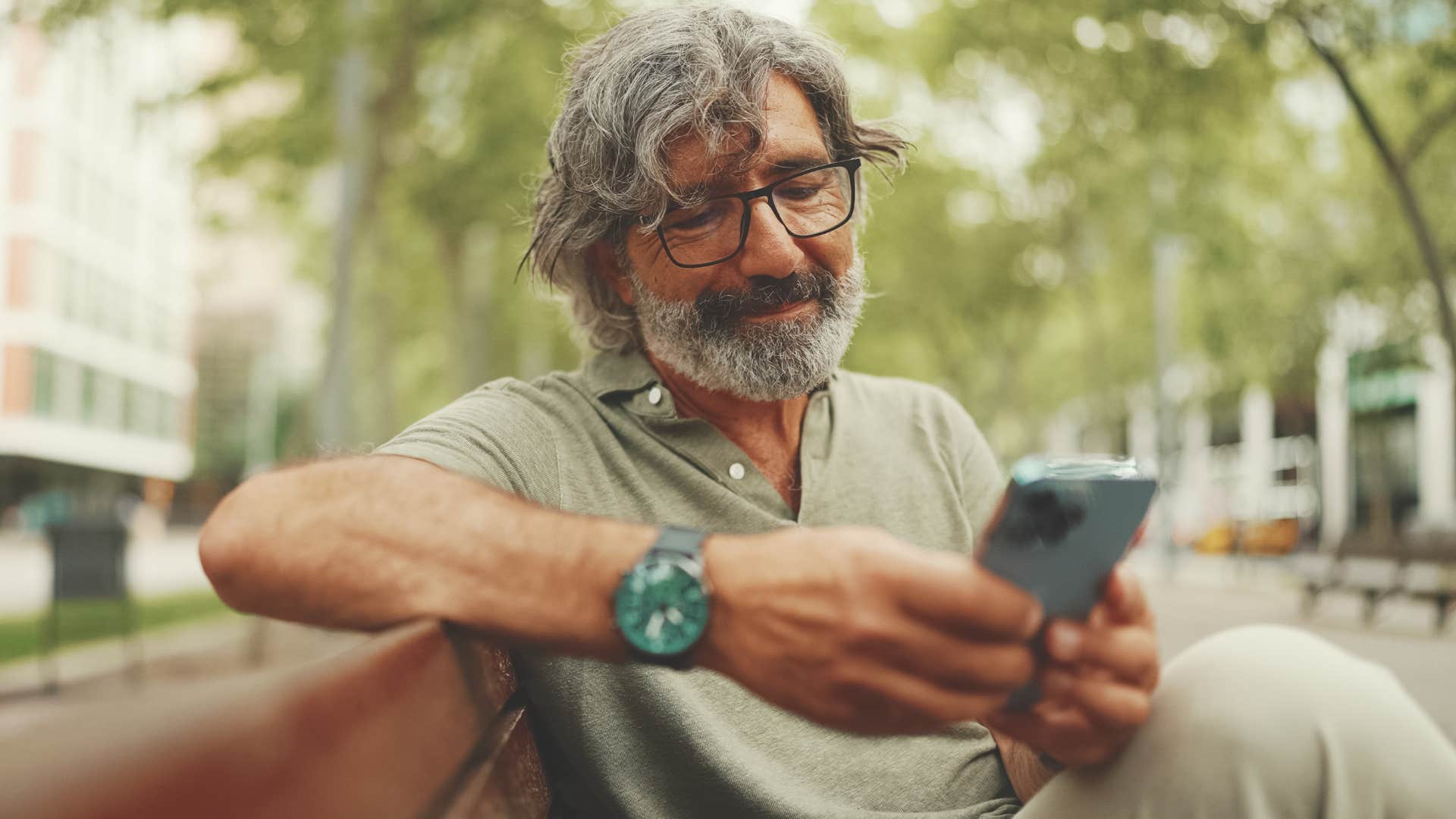 Man who appreciates independence looking at his phone outside.