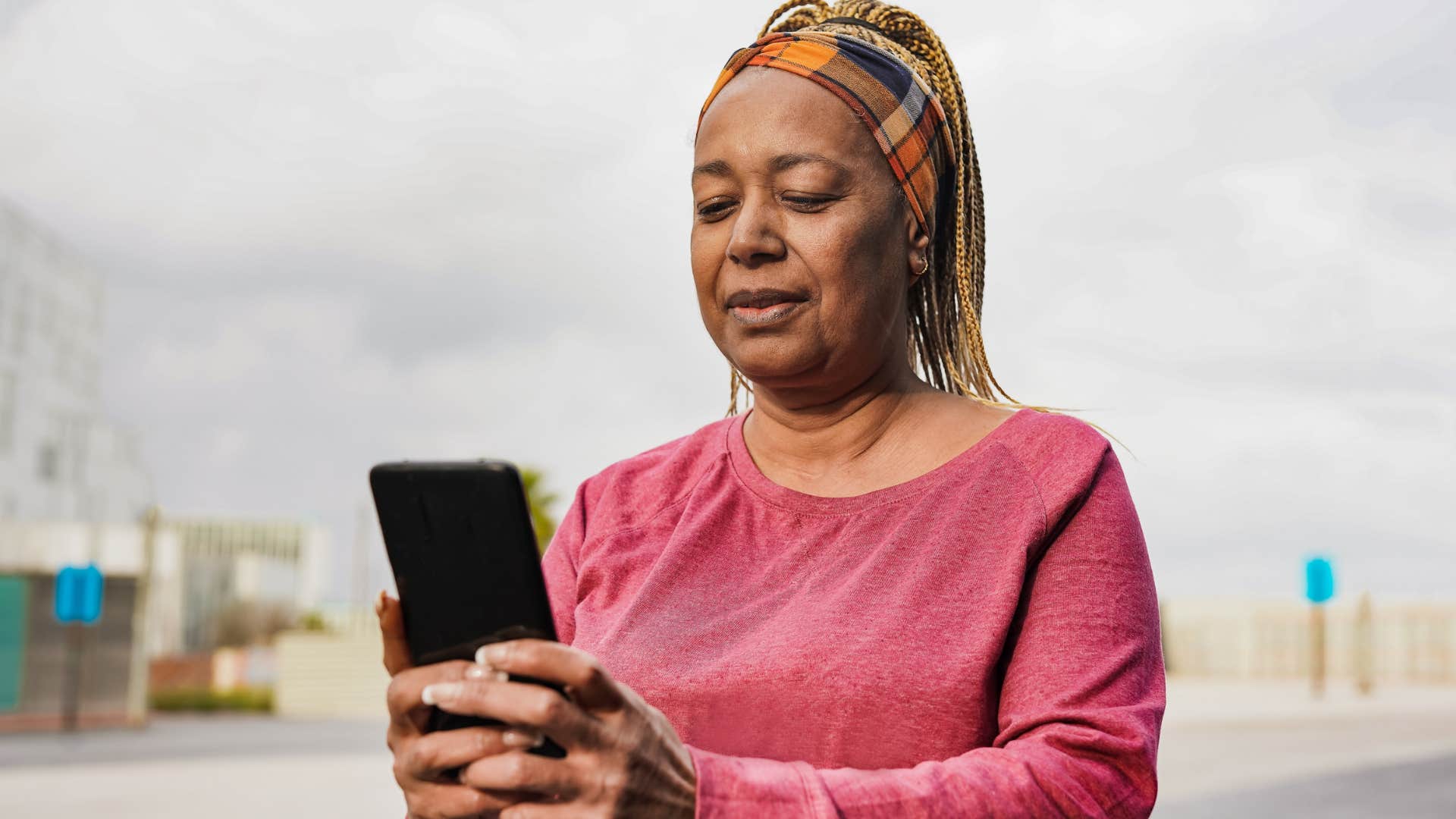 Baby boomer woman with patience smiling and typing on her phone.