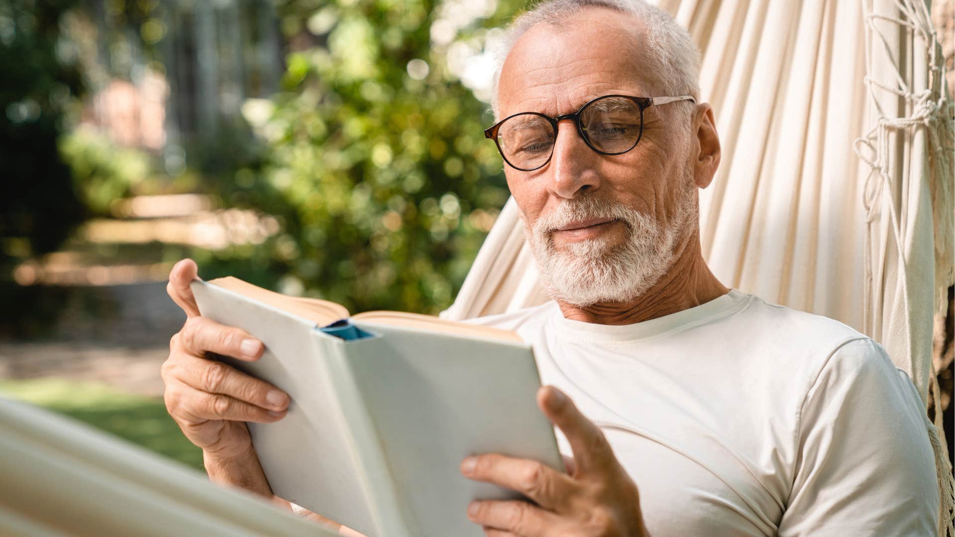 Man with great reading comprehension looking at a book outside.
