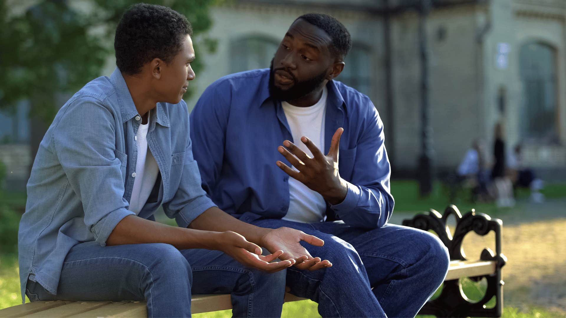 son being rude to his nice parent as dad sits on the bench and tries to explain something to him