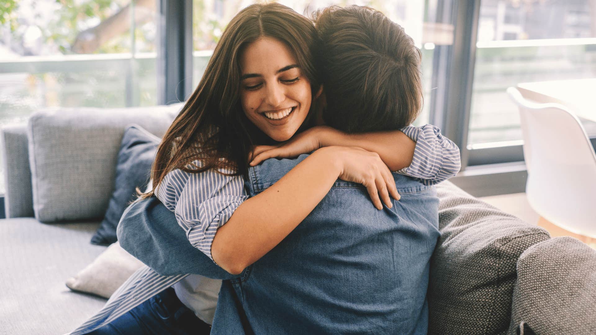 couple hugging one another on the couch while woman smiles as she makes her significant other her entire personality