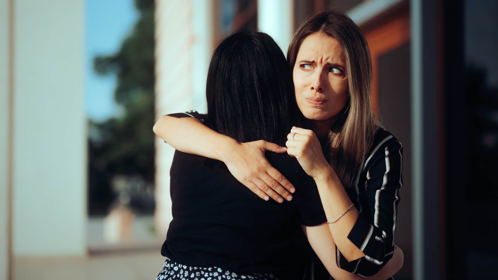 friend being weirdly posessive over other friend as she looks uncomfortable while hugging her