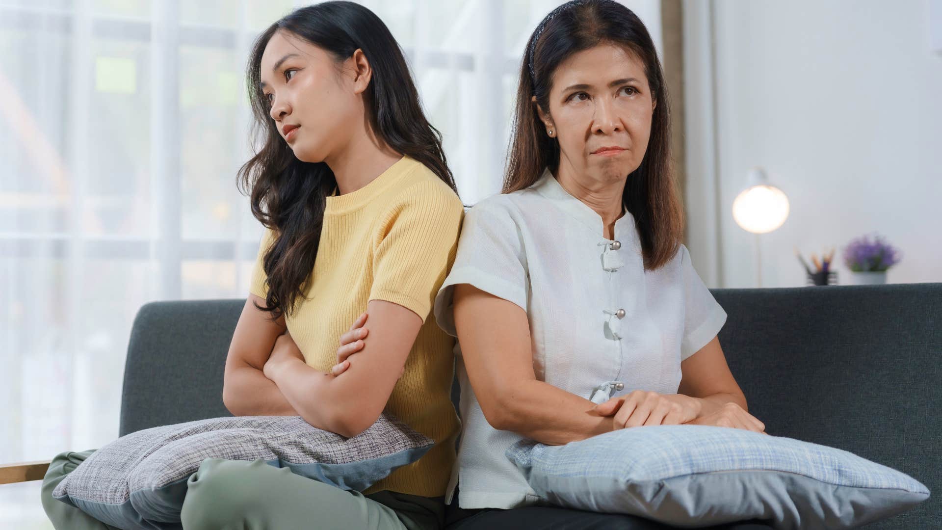 upset mother and adult daughter sitting on couch