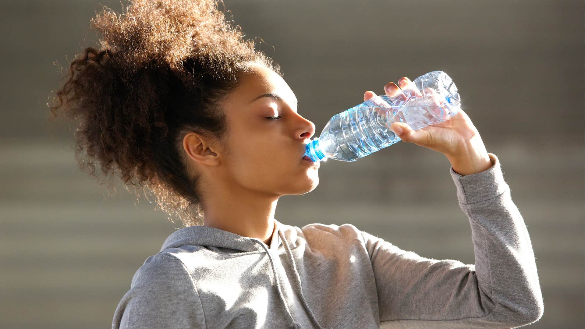 woman drinking bottled water after exercising