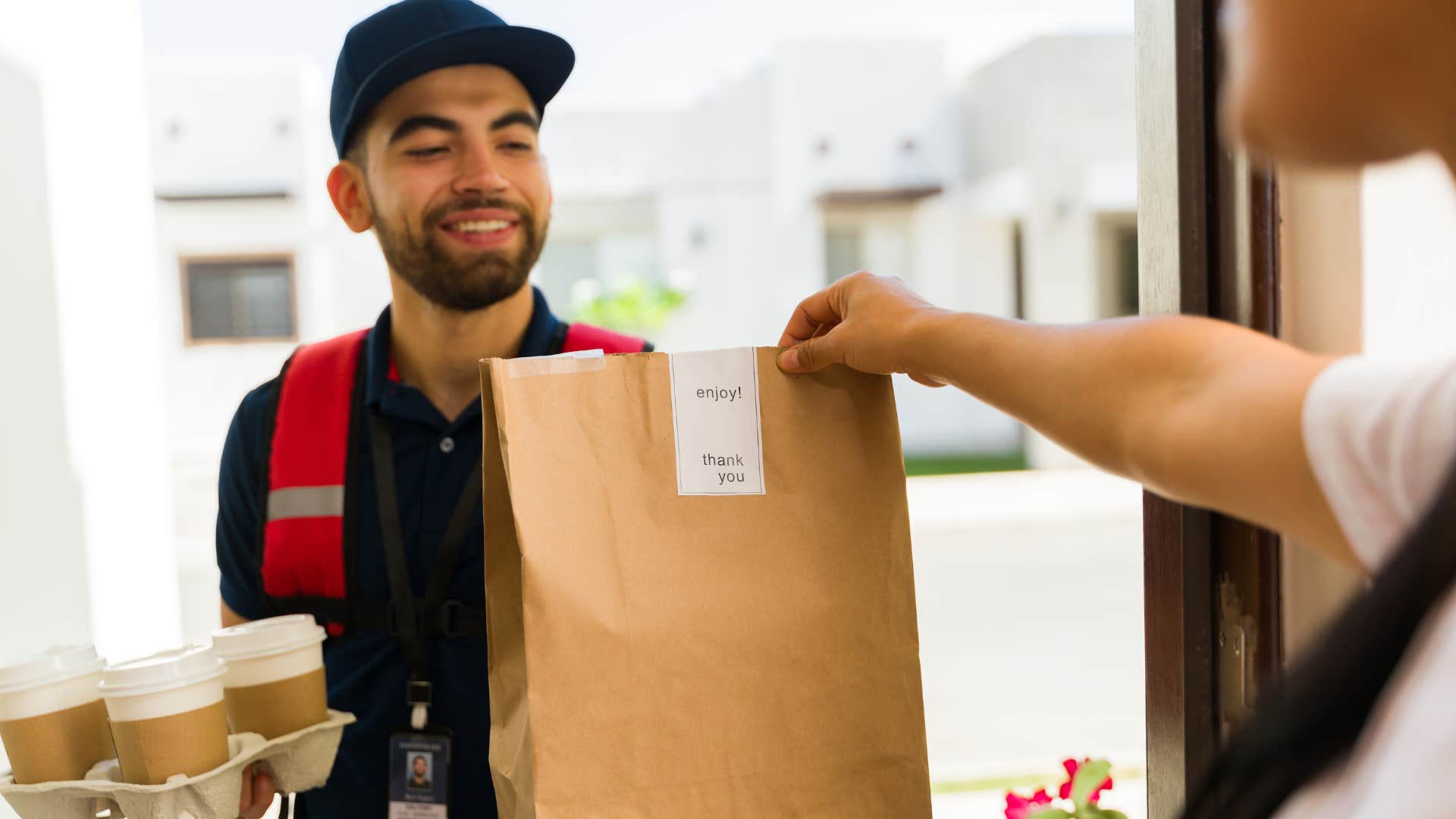 woman grabbing a bag from a food delivery service worker