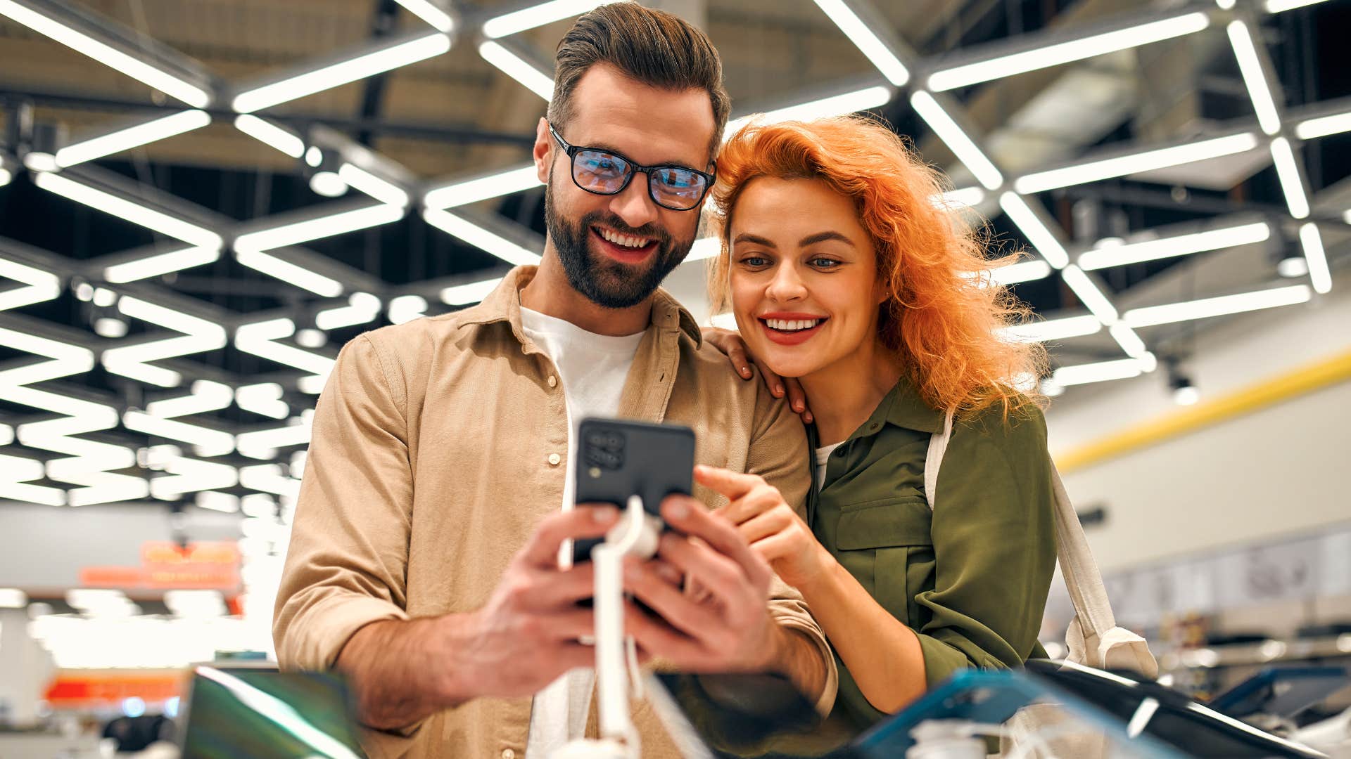 couple looking at a new phone and talking about extended warranties