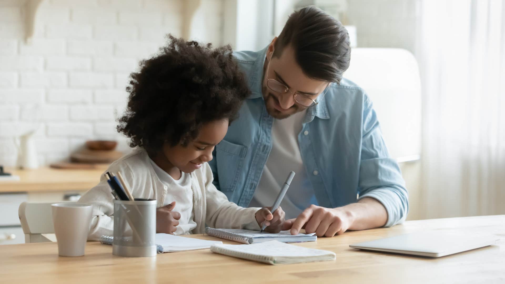 man teaching his daughter critical thinking skills doing homework