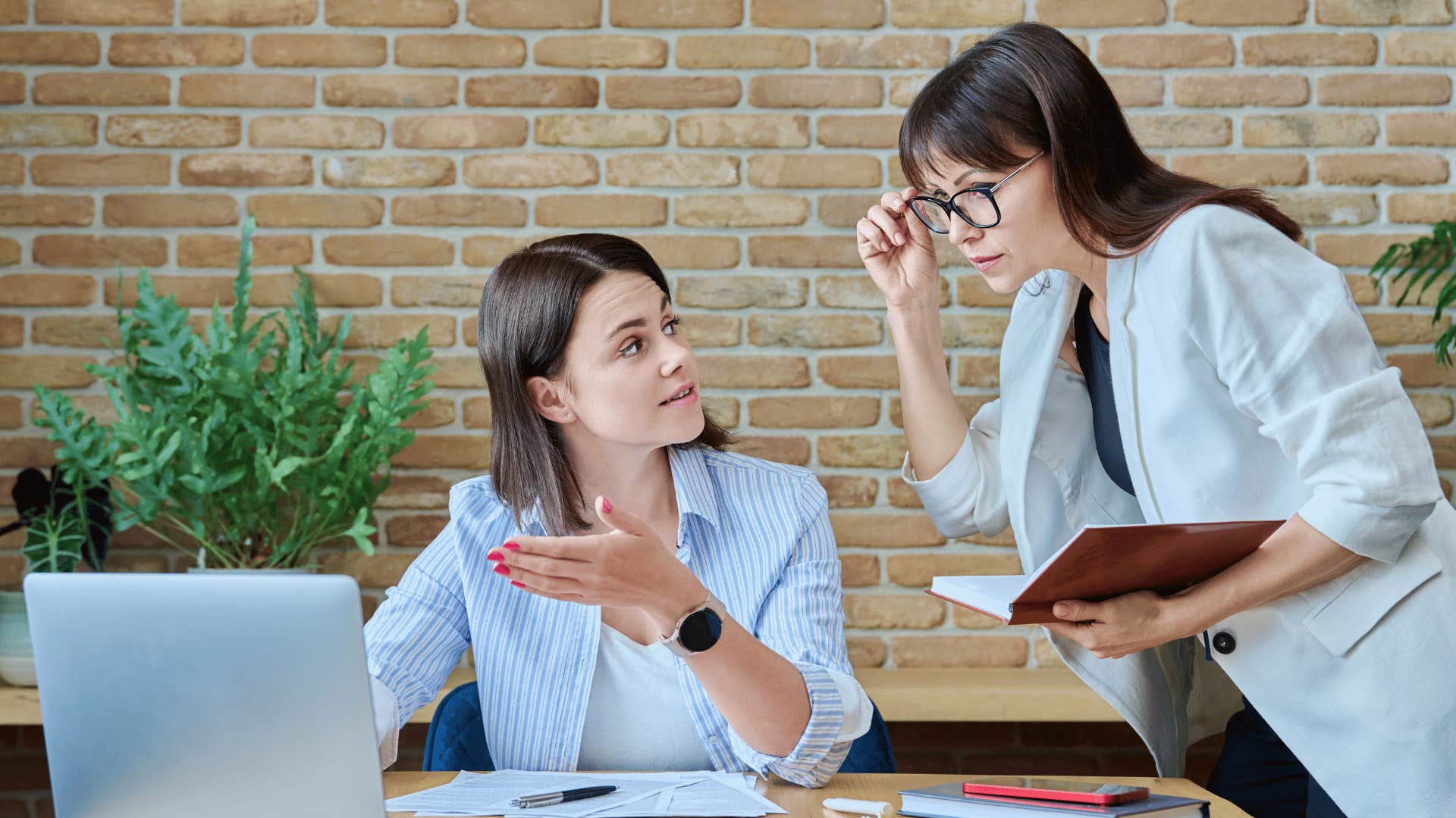 boss micromanaging at workplace and employee stares at her annoyed