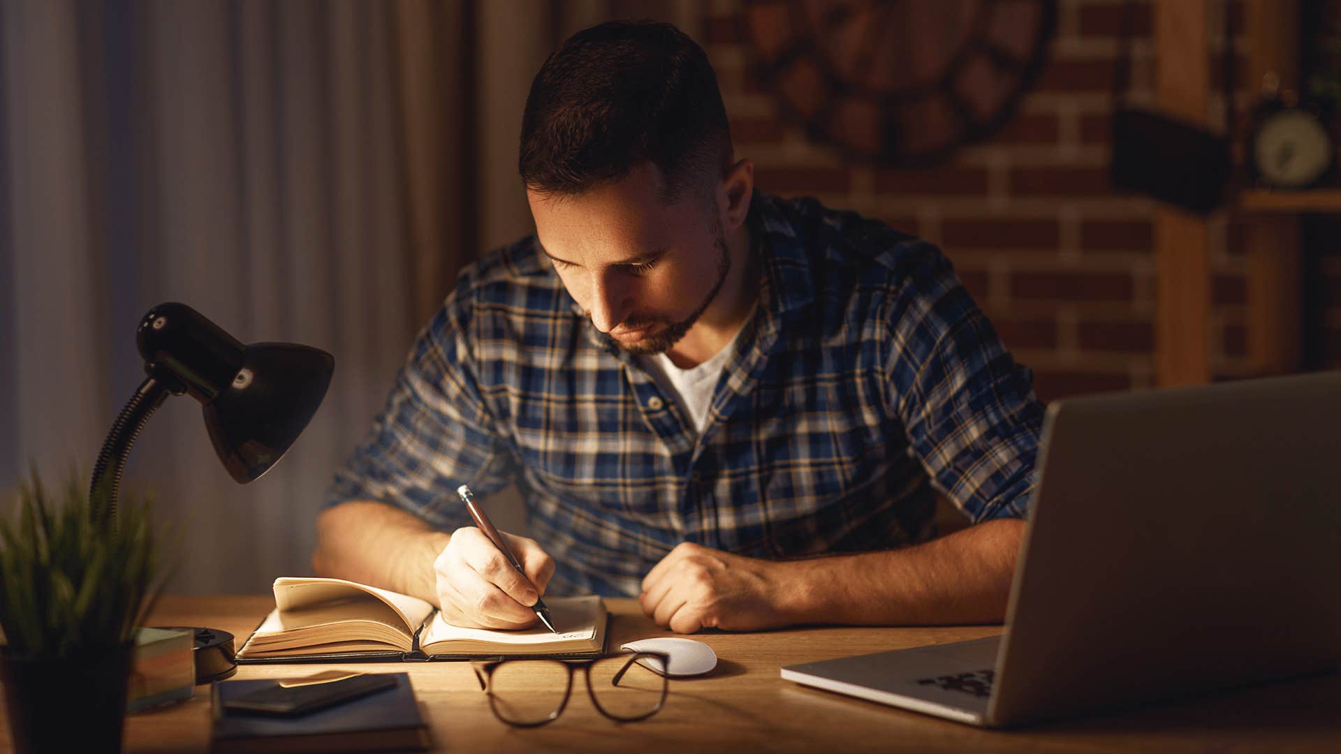 man working outside work hours and writing something down in notebook