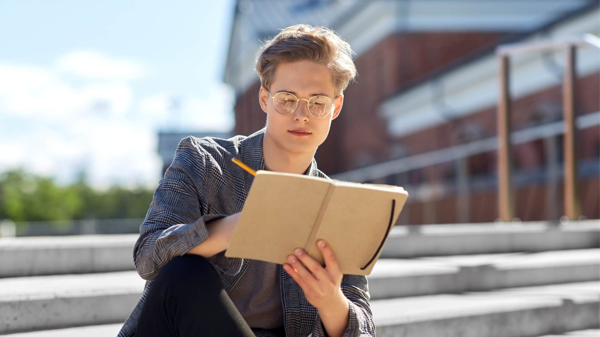 Gen Z man writes in his journal outside to cope with stress