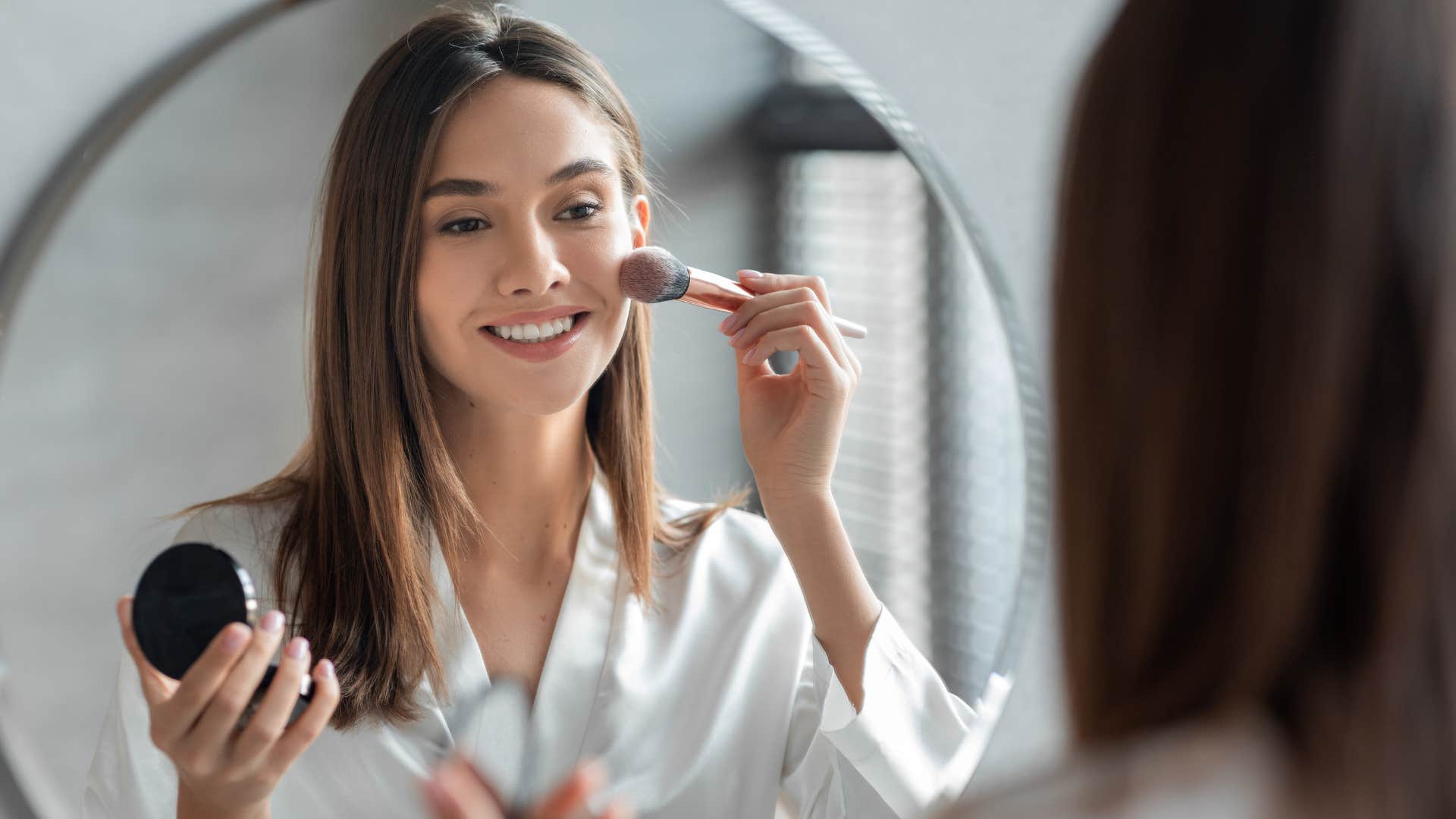 woman putting on makeup in a mirror
