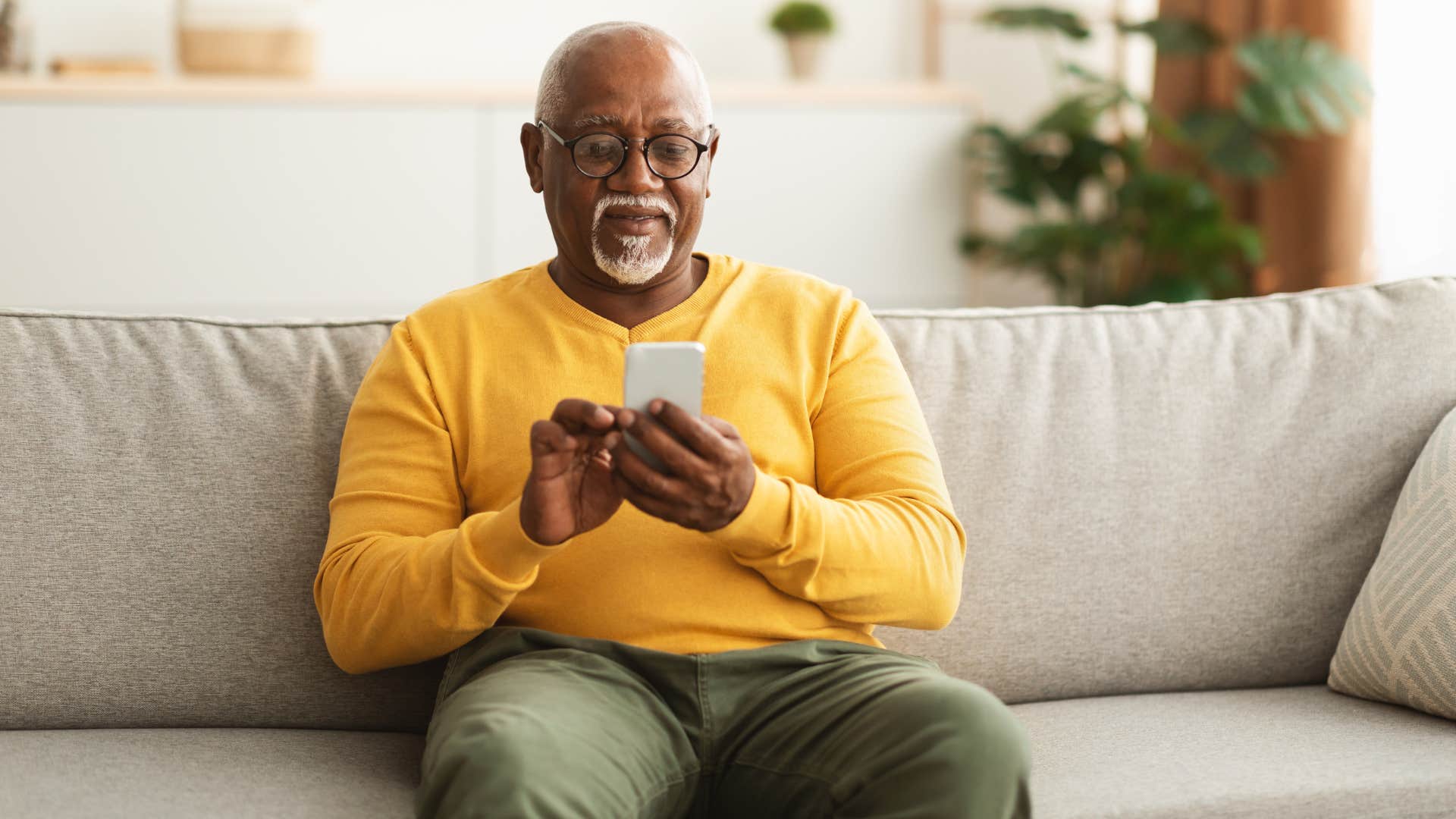 man texting his wife sitting on couch