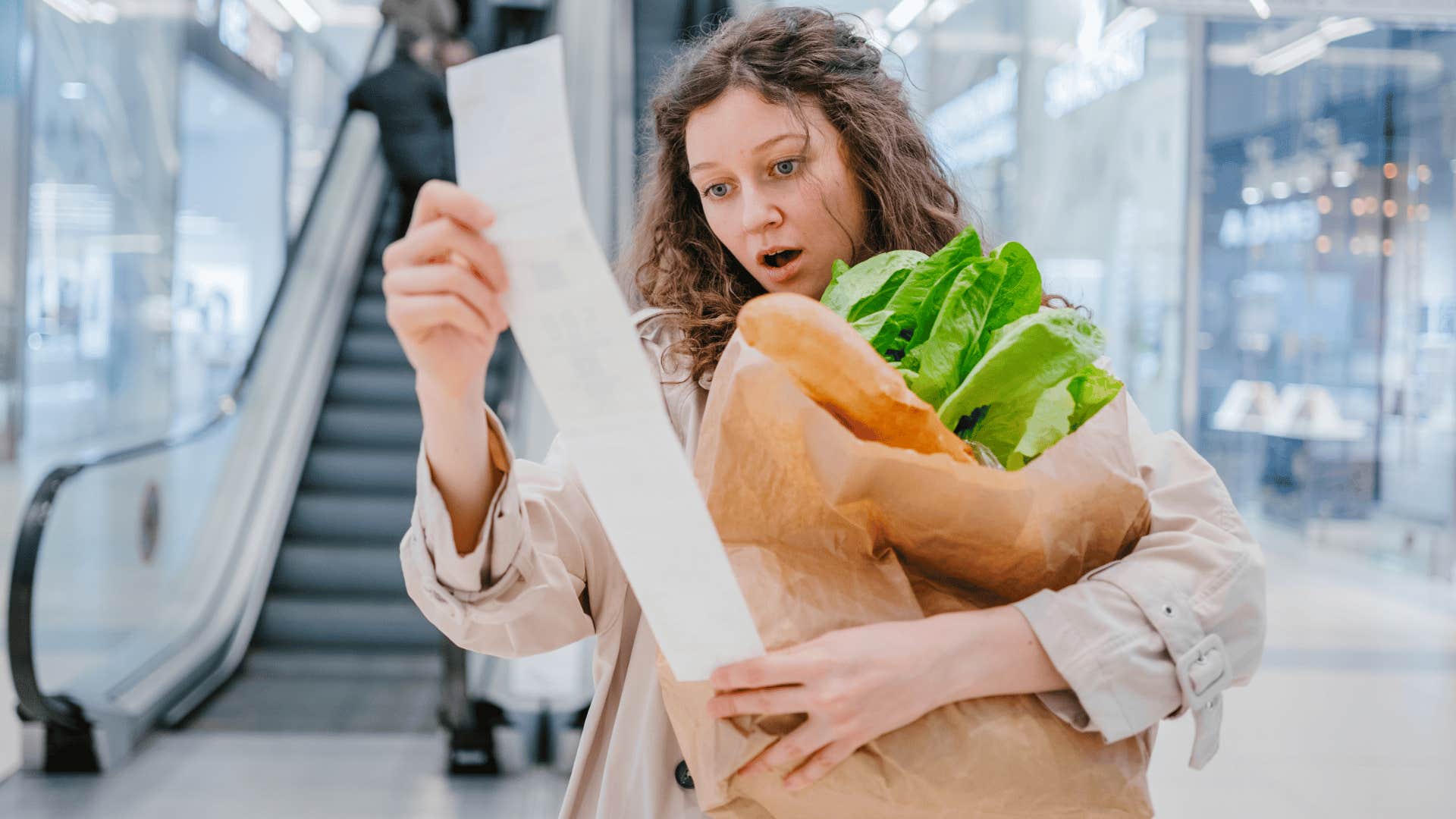 shocked woman looking at grocery store receipt