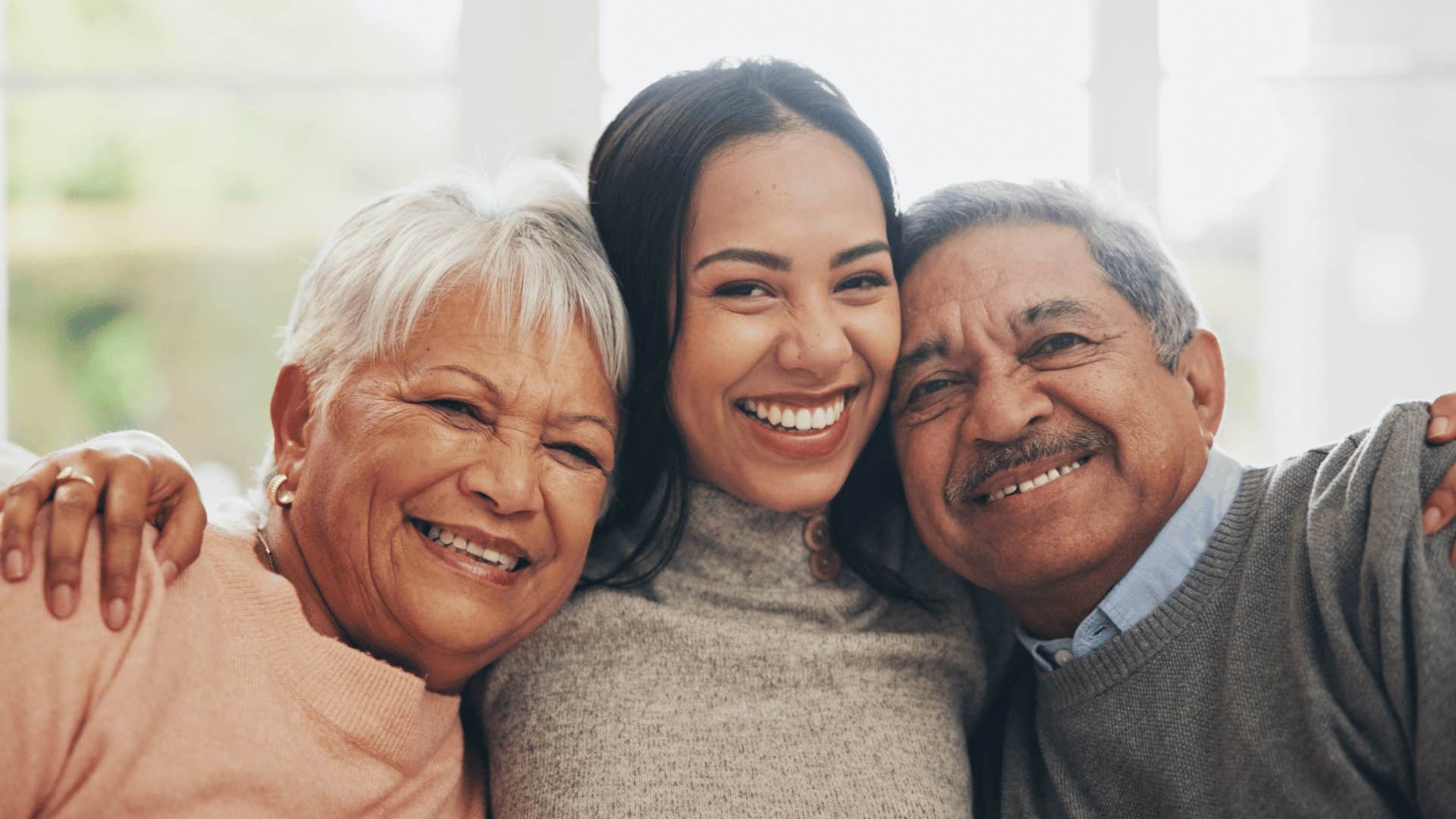 millennial woman hugging her happy parents