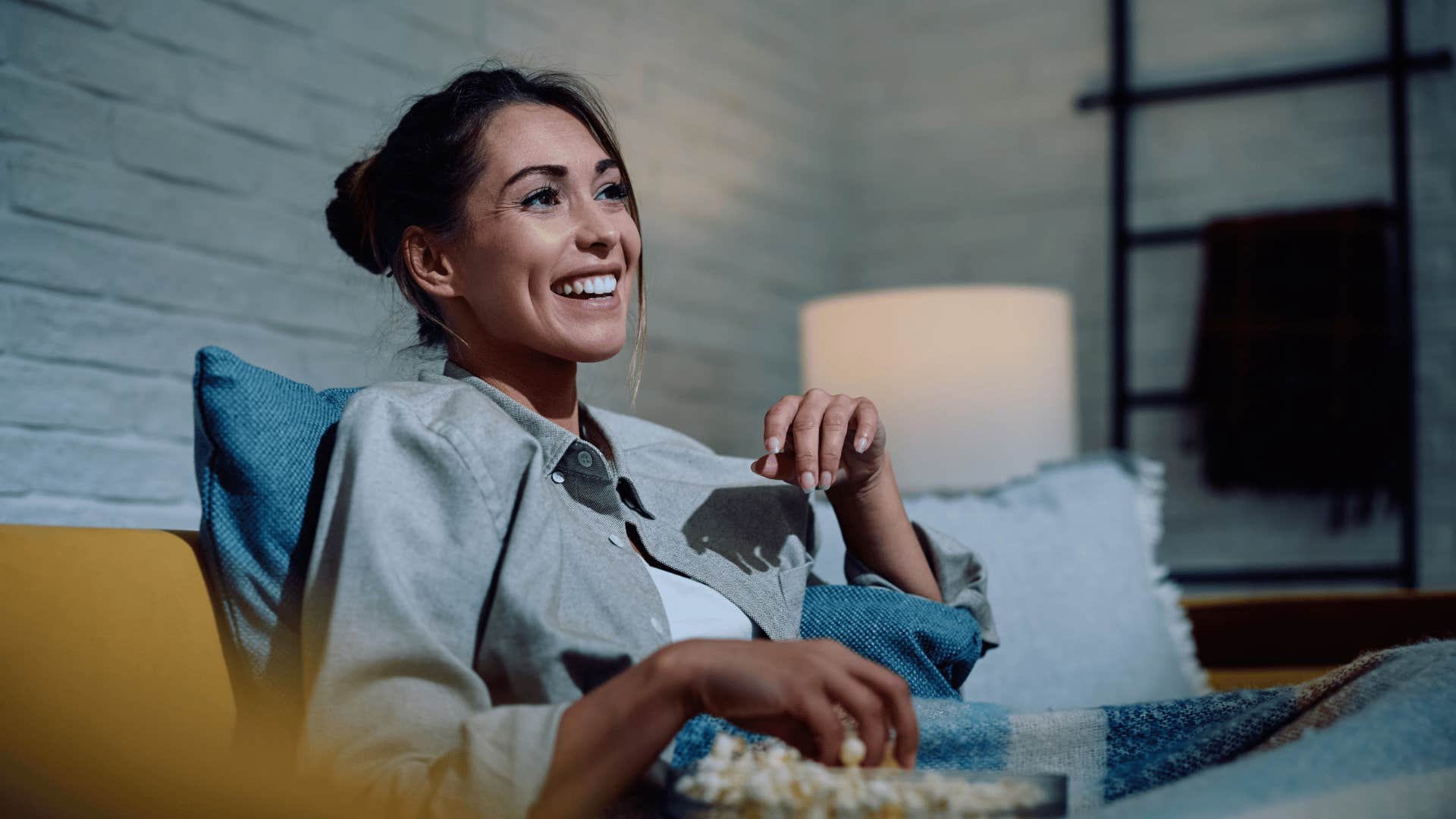 smiling millennial woman watching a movie at night